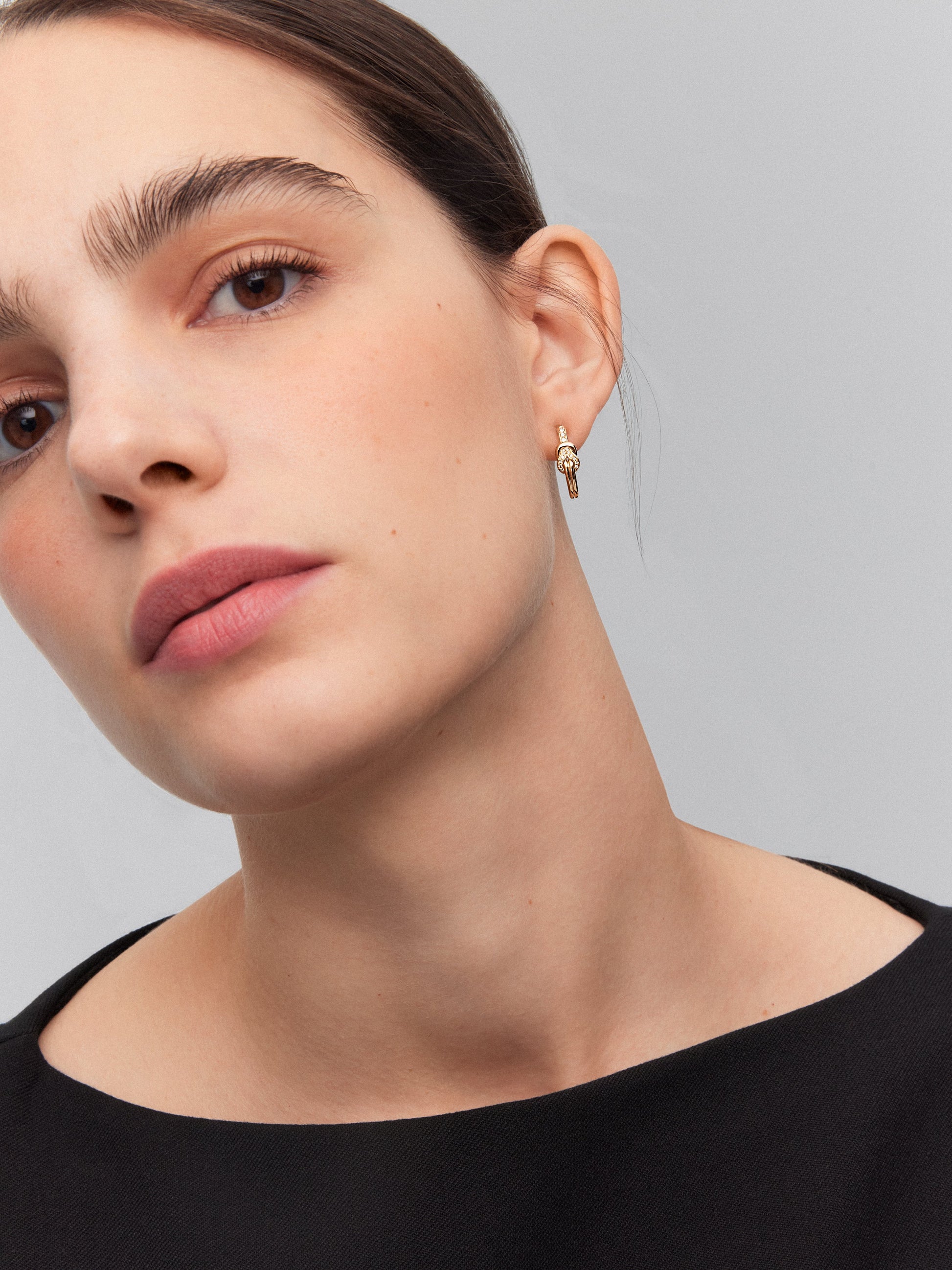 Pendientes de aro de oro amarillo de 18K con diamantes blancos en talla brillante de 0,11 cts y forma de nudo