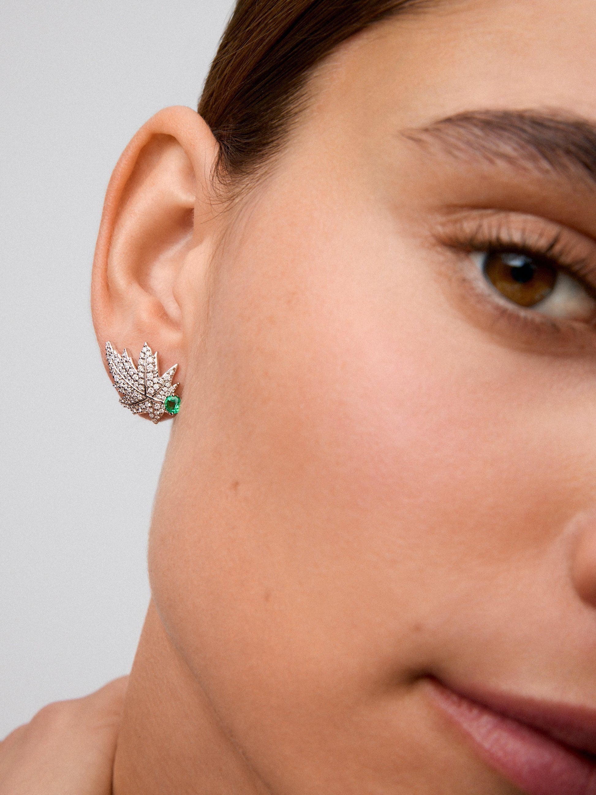 Pendientes de oro blanco de 18K con 2 esmeraldas centrales con un total de 0,28 cts, pavé de diamantes y forma de hoja de arce