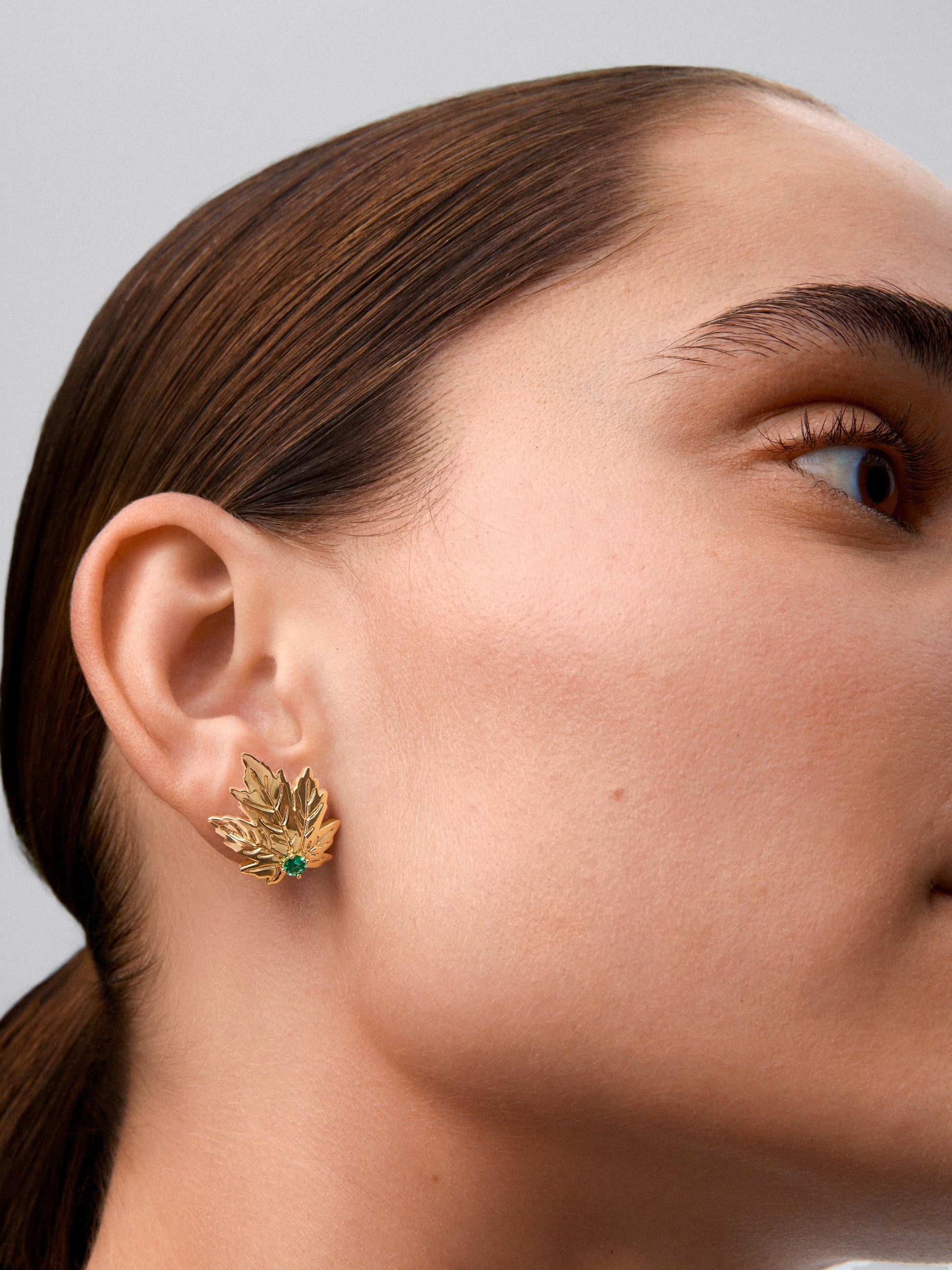 Pendientes de oro amarillo de 18K con 2 esmeraldas centrales en talla brillante con un total de 0,33 cts y forma de hoja de arce