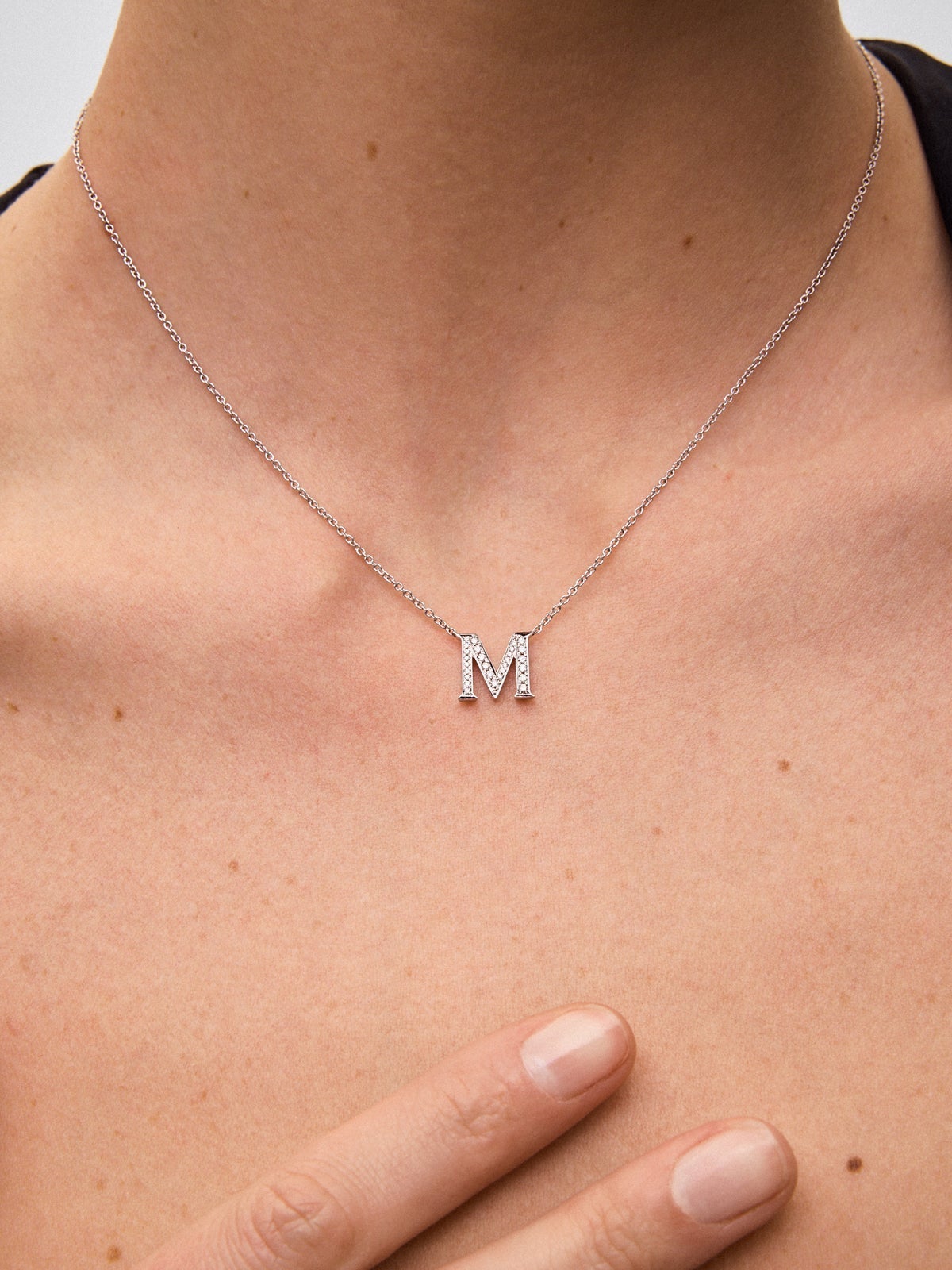 Colgante de oro blanco de 18K con letra M en pavé de 28 diamantes en talla brillante con un total de 0,13 cts