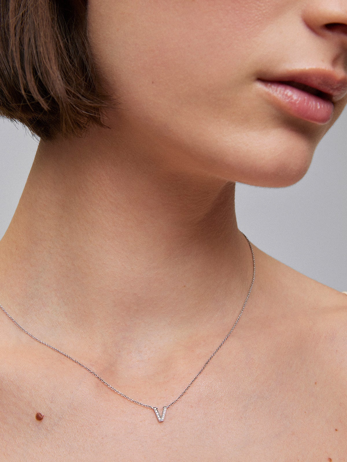 Colgante de oro blanco de 18K con diamantes en talla brillante de 0,03 cts y letra V