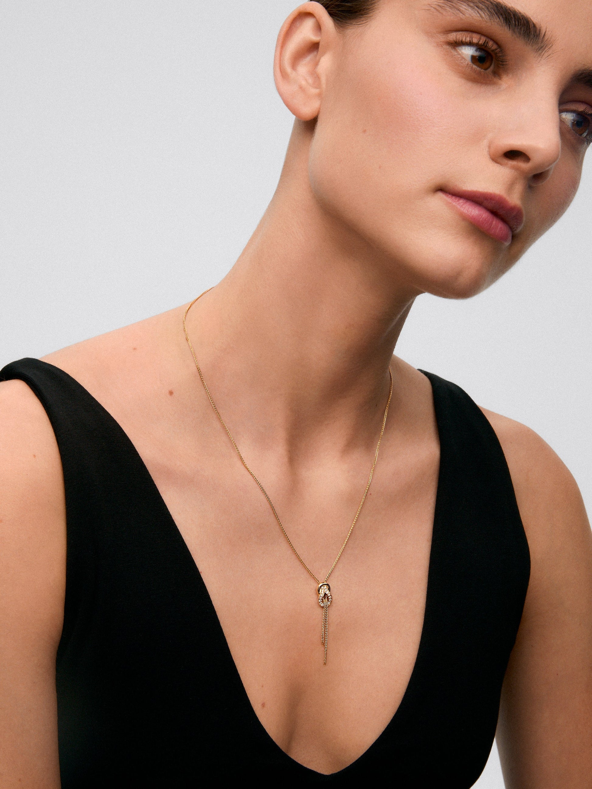 Colgante de oro amarillo de 18K con 26 diamantes en talla brillante con un total de 0,16 cts y forma de nudo