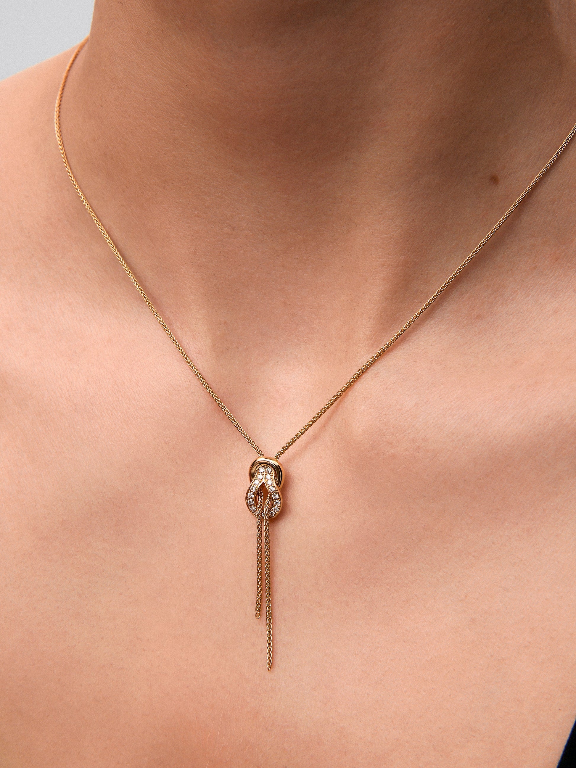 Colgante de oro amarillo de 18K con 26 diamantes en talla brillante con un total de 0,16 cts y forma de nudo