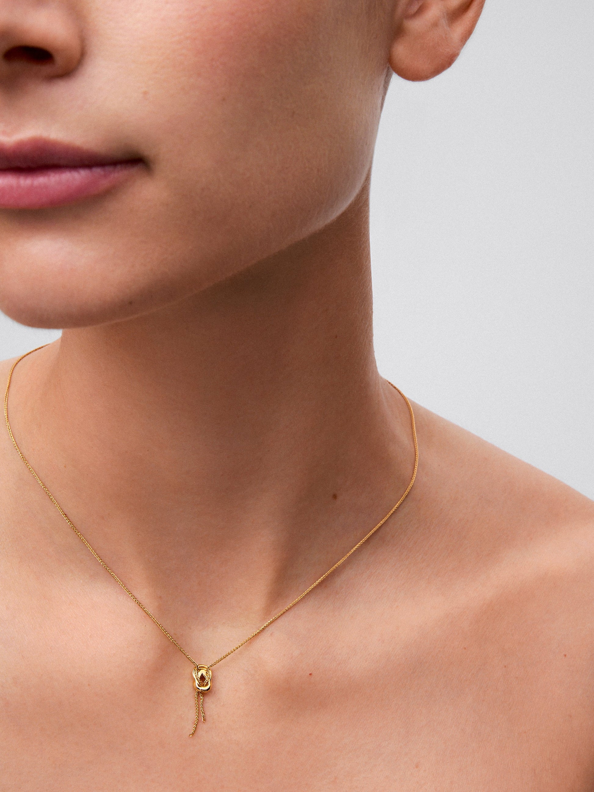 Colgante de oro amarillo de 18K con diamantes blancos en talla brillante de 0,05 cts y forma de nudo