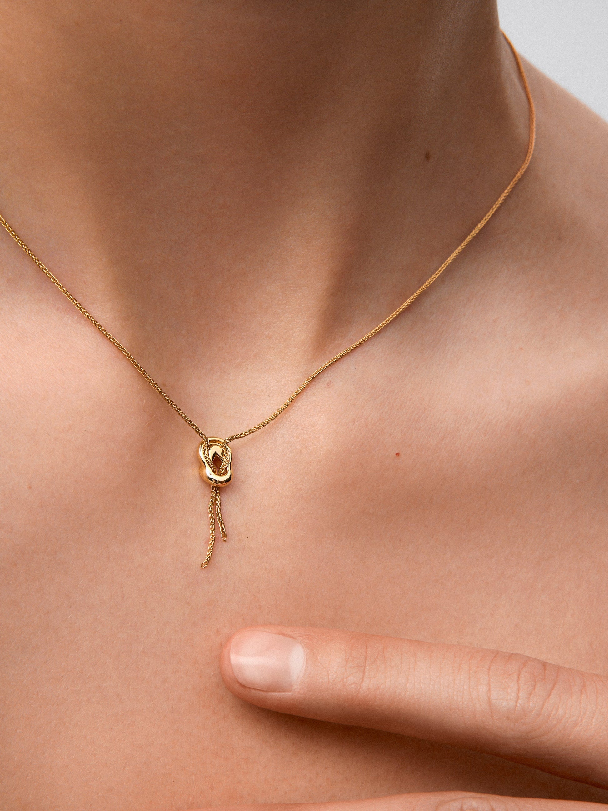Colgante de oro amarillo de 18K con diamantes blancos en talla brillante de 0,05 cts y forma de nudo