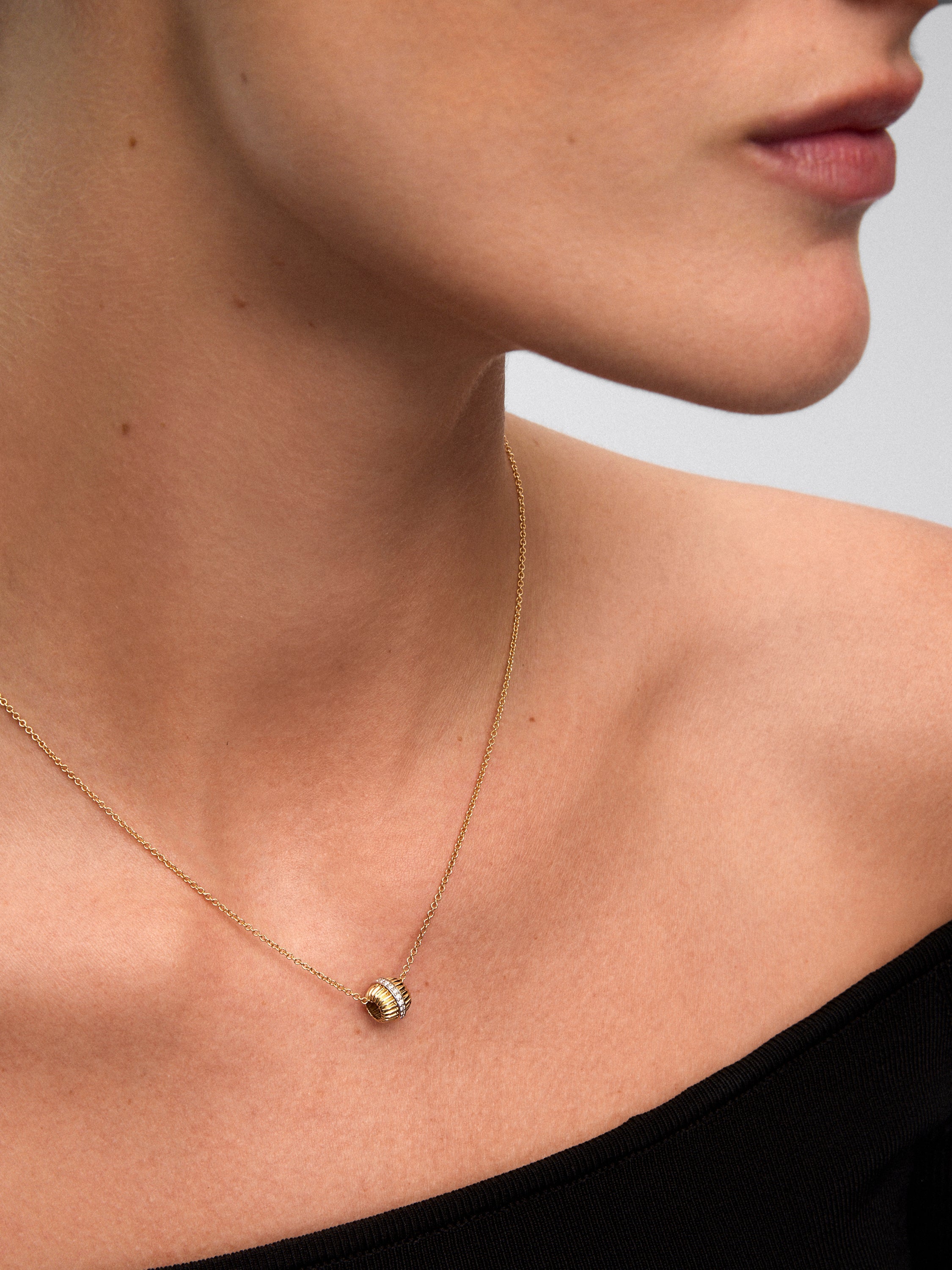 Colgante gallonado de oro blanco y amarillo de 18K con pavé de diamantes en talla brillante con un total de 0,115 cts