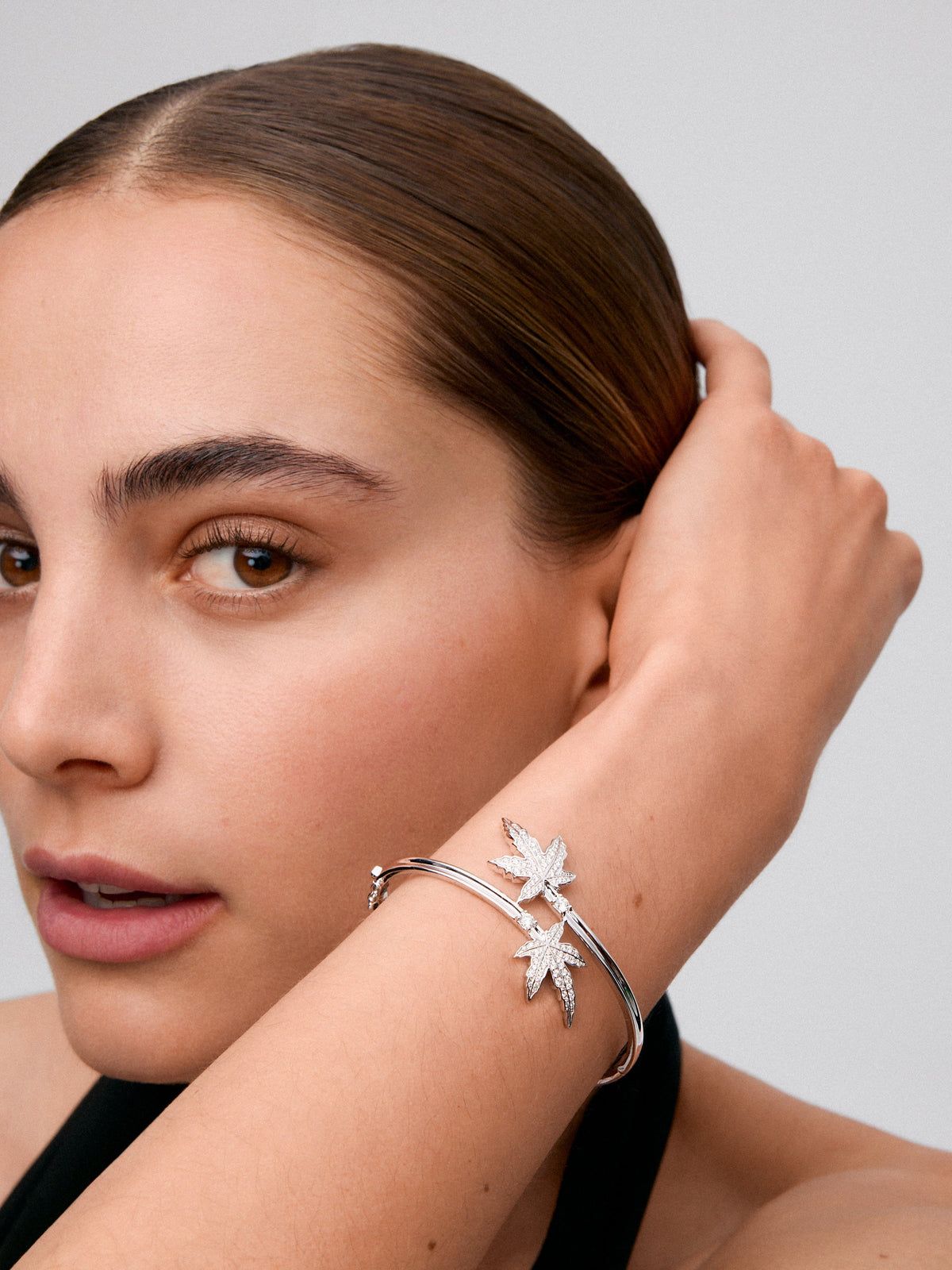 Pulsera de oro blanco de 18K con diamante central en talla brillante de 0,14 cts, pavé de diamantes y forma de hoja de arce