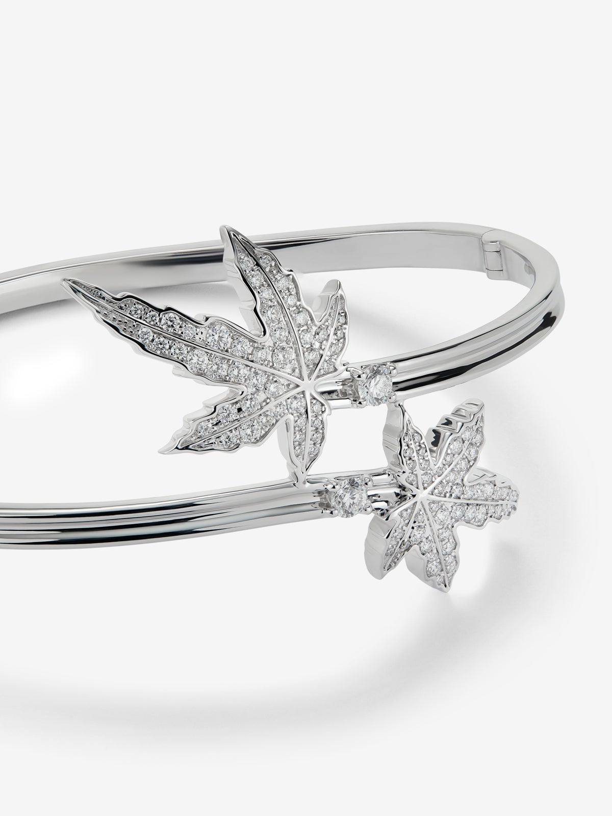Pulsera de oro blanco de 18K con diamante central en talla brillante de 0,14 cts, pavé de diamantes y forma de hoja de arce