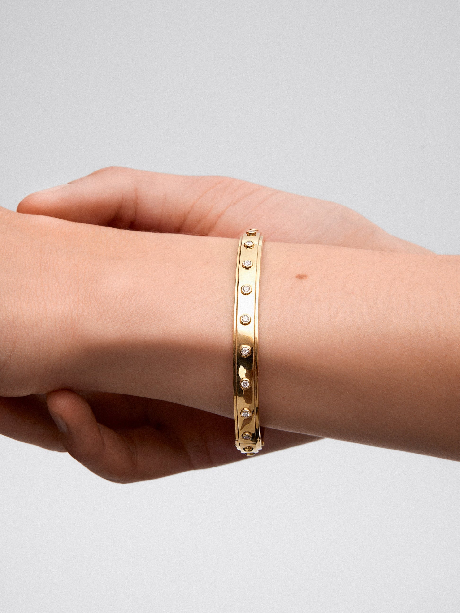 Pulsera rígida de oro amarillo de 18K con 11 diamantes en talla brillante con un total de 0,36 cts