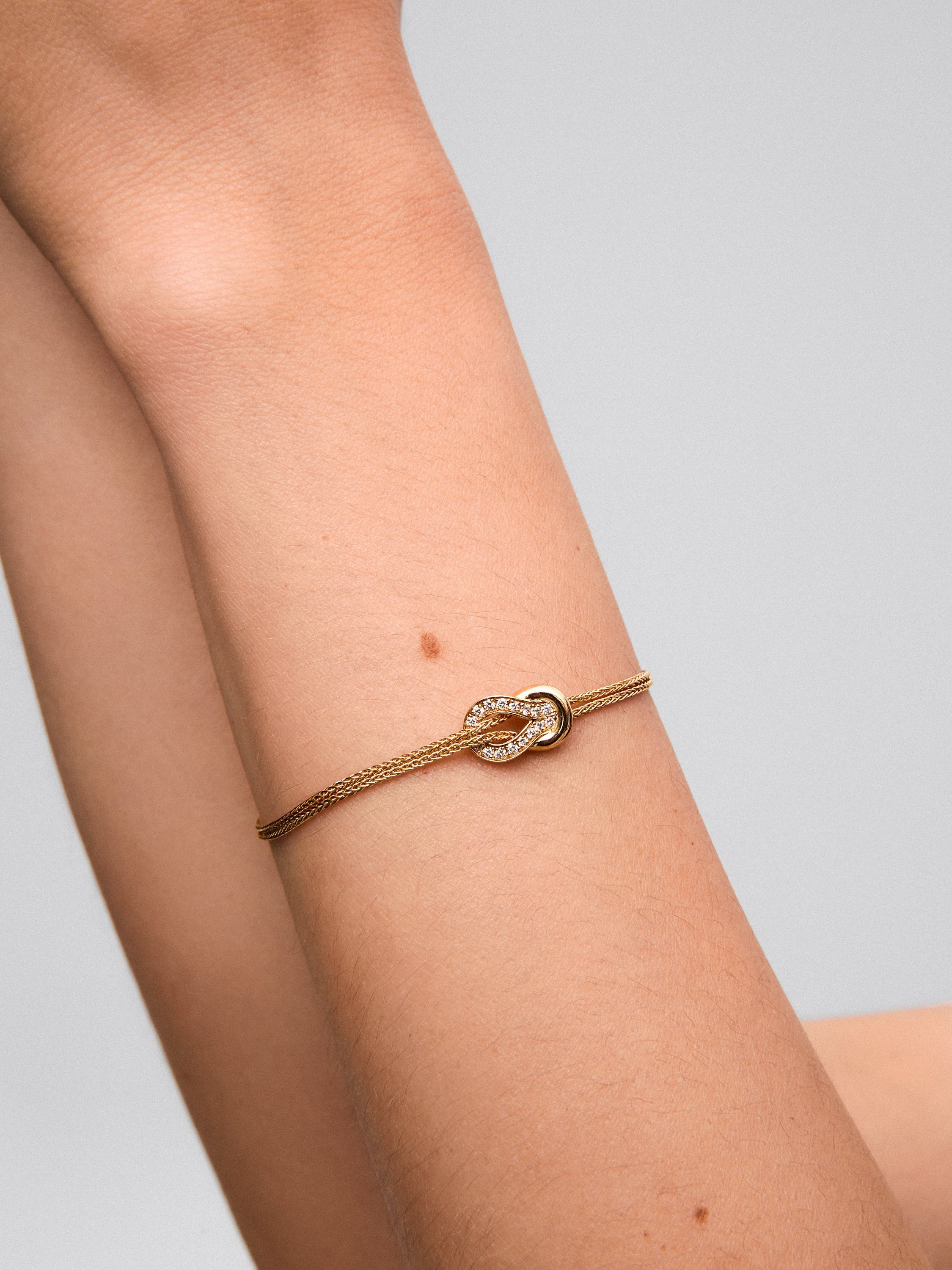 Pulsera de oro amarillo de 18K con 17 diamantes en talla brillante con un total de 0,15 cts y forma de nudo