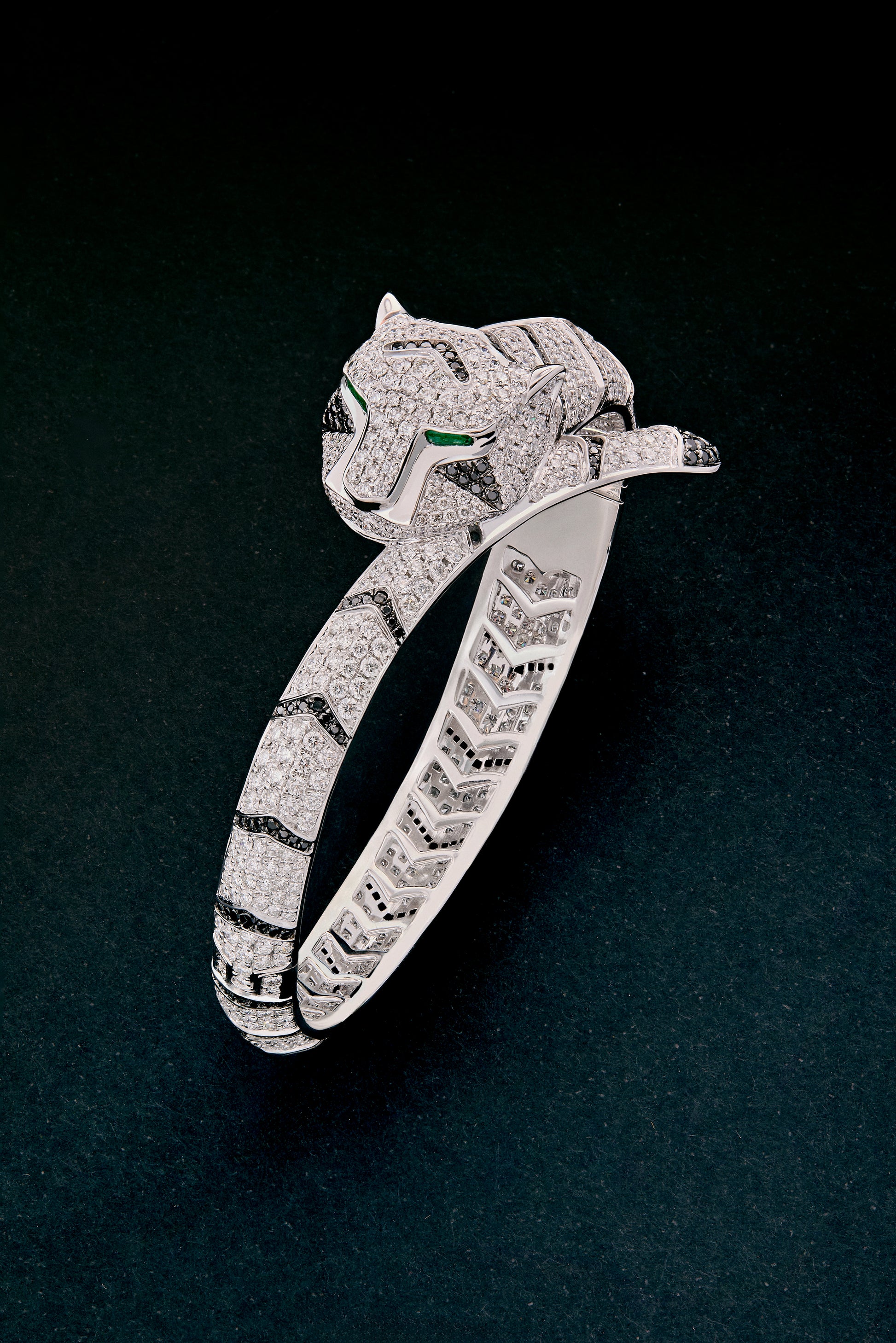 Pulsera rígida de oro blanco de 18K con 747 diamantes blancos en talla brillante con un total de 8,17 cts, 241 diamantes negros en talla brillante con un total de 1,49 cts  y 2 esmeraldas en talla trapecio con un total de 0,13 cts con forma de tigre