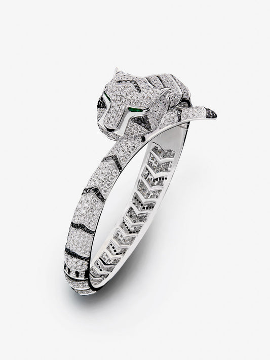 Pulsera rígida con forma de tigre en oro blanco de 18K con diamantes blancos y negros en talla brillante con un total de 9,66 cts y esmeraldas en talla trapecio con un total de 0,13 cts