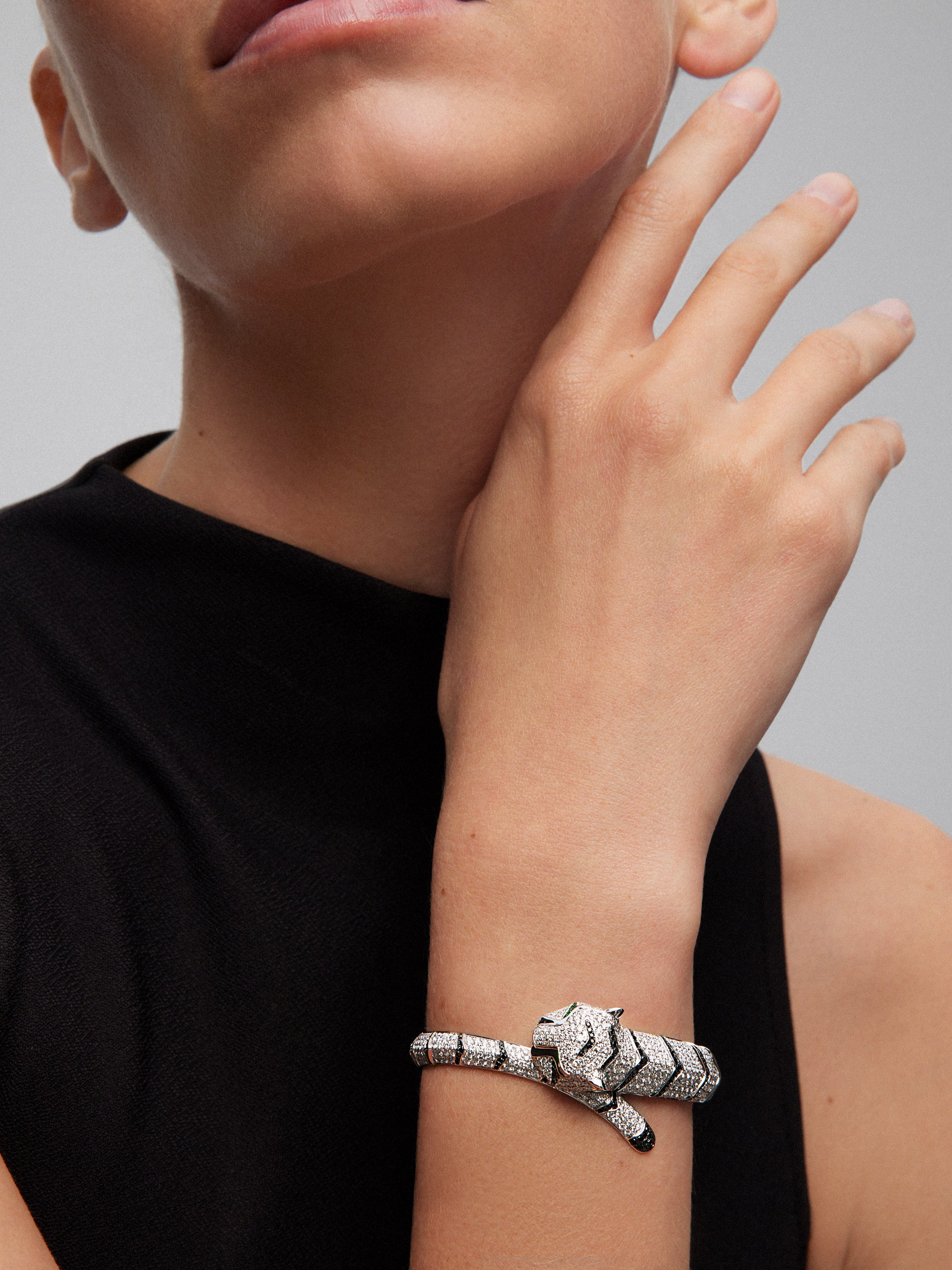 Pulsera rígida de oro blanco de 18K con 747 diamantes blancos en talla brillante con un total de 8,17 cts, 241 diamantes negros en talla brillante con un total de 1,49 cts  y 2 esmeraldas en talla trapecio con un total de 0,13 cts con forma de tigre