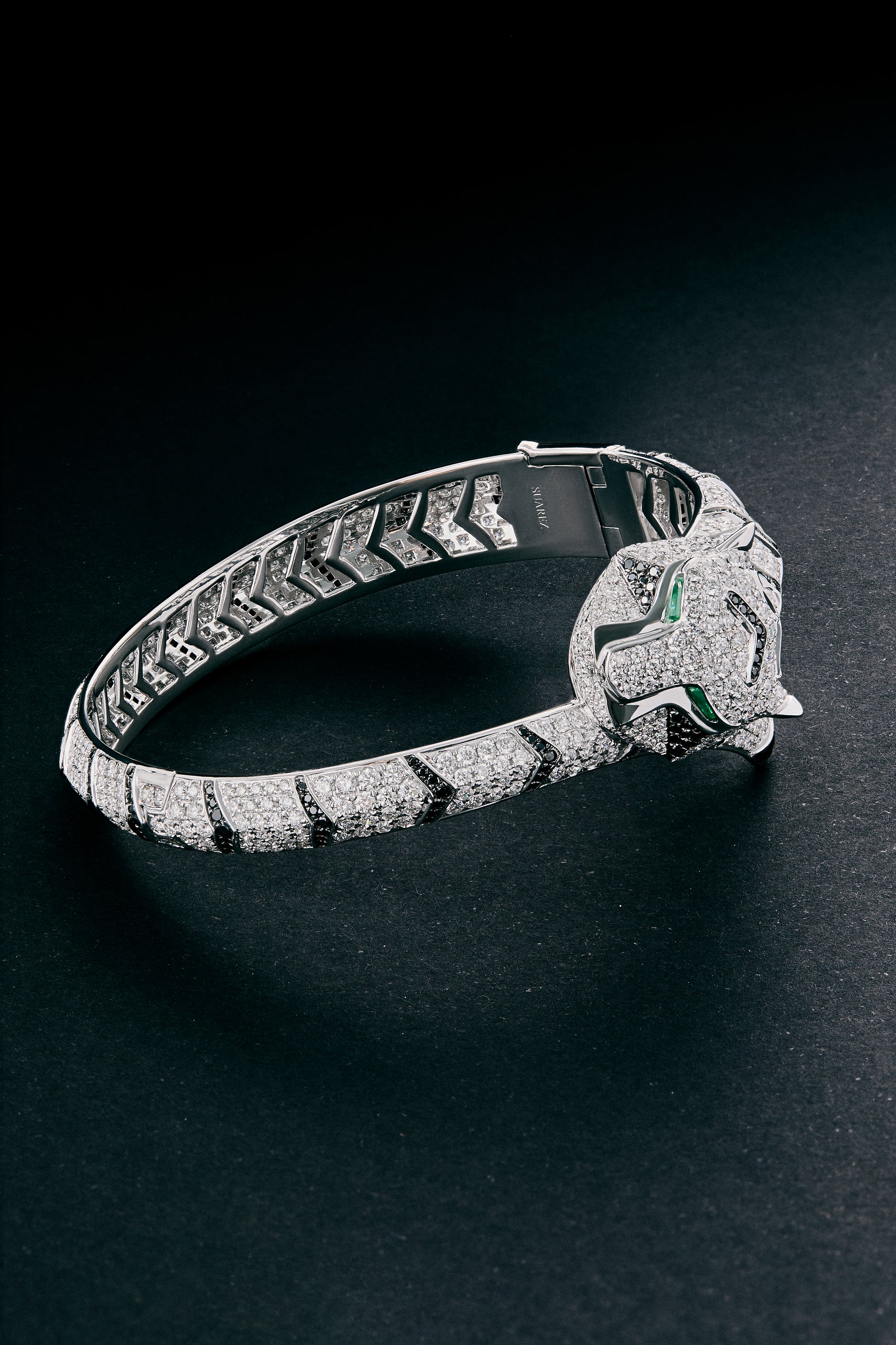 Pulsera rígida de oro blanco de 18K con 747 diamantes blancos en talla brillante con un total de 8,17 cts, 241 diamantes negros en talla brillante con un total de 1,49 cts  y 2 esmeraldas en talla trapecio con un total de 0,13 cts con forma de tigre