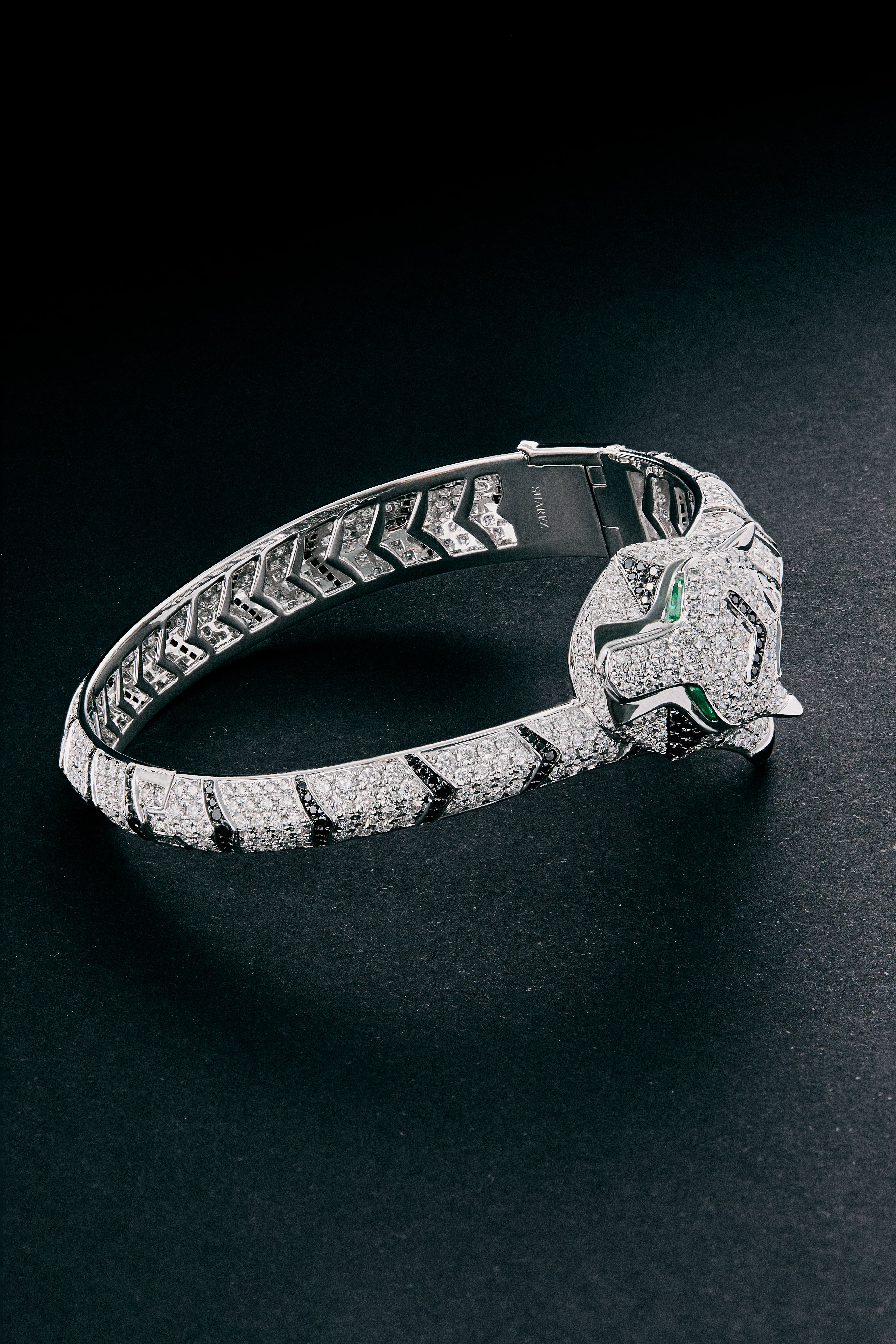 Pulsera rígida de oro blanco de 18K con 747 diamantes blancos en talla brillante con un total de 8,17 cts, 241 diamantes negros en talla brillante con un total de 1,49 cts  y 2 esmeraldas en talla trapecio con un total de 0,13 cts con forma de tigre