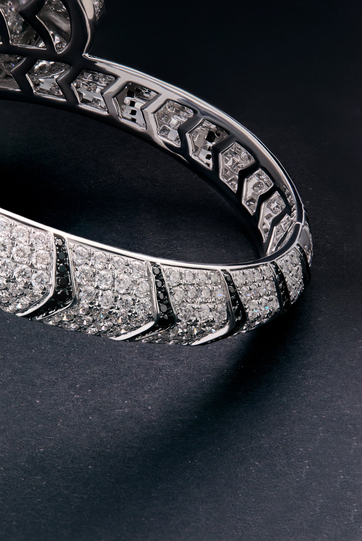 Pulsera rígida con forma de tigre en oro blanco de 18K con diamantes blancos y negros en talla brillante con un total de 9,66 cts y esmeraldas en talla trapecio con un total de 0,13 cts 