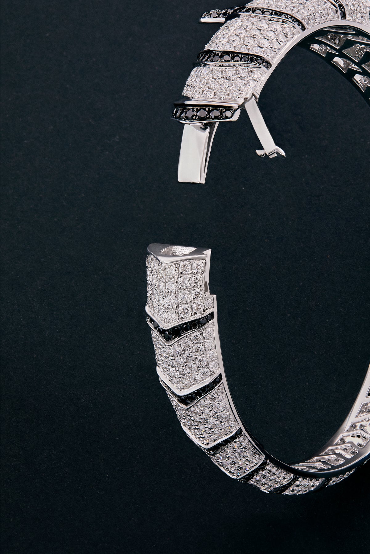 Pulsera rígida de oro blanco de 18K con 747 diamantes blancos en talla brillante con un total de 8,17 cts, 241 diamantes negros en talla brillante con un total de 1,49 cts  y 2 esmeraldas en talla trapecio con un total de 0,13 cts con forma de tigre