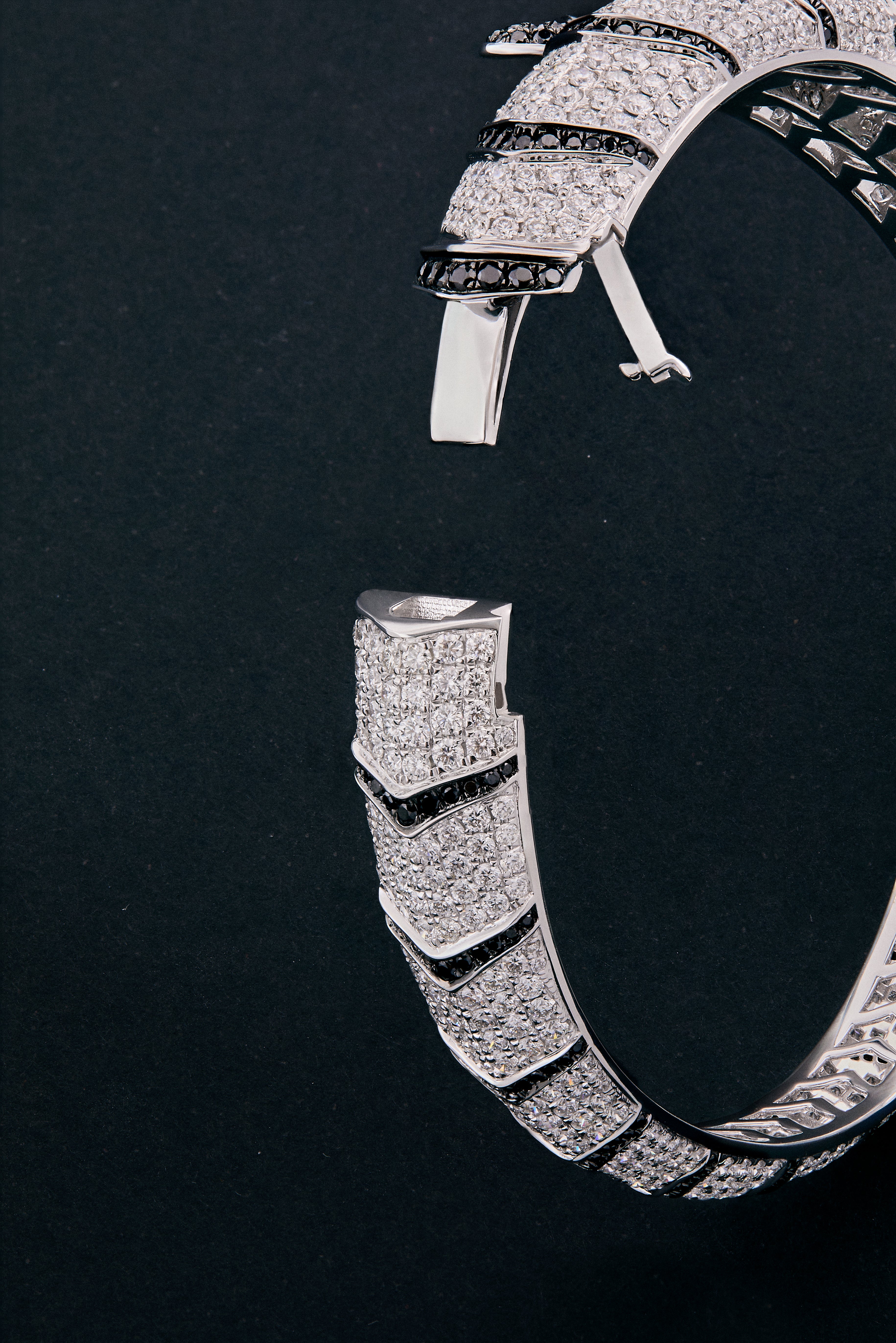 Pulsera rígida de oro blanco de 18K con 747 diamantes blancos en talla brillante con un total de 8,17 cts, 241 diamantes negros en talla brillante con un total de 1,49 cts  y 2 esmeraldas en talla trapecio con un total de 0,13 cts con forma de tigre