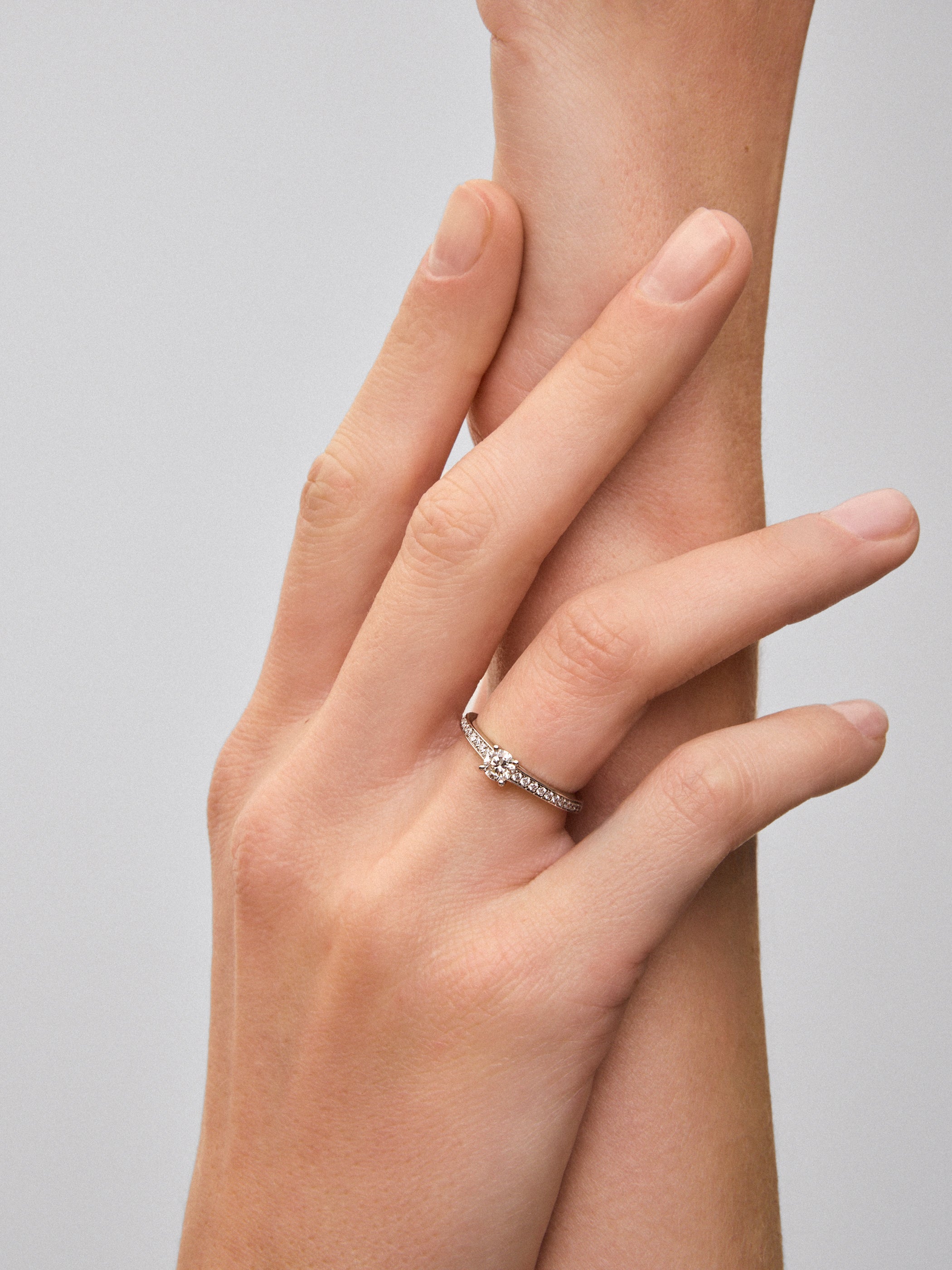 Anillo solitario de oro blanco de 18K con diamante central de 0,30 cts y brazo de diamantes en talla brillante