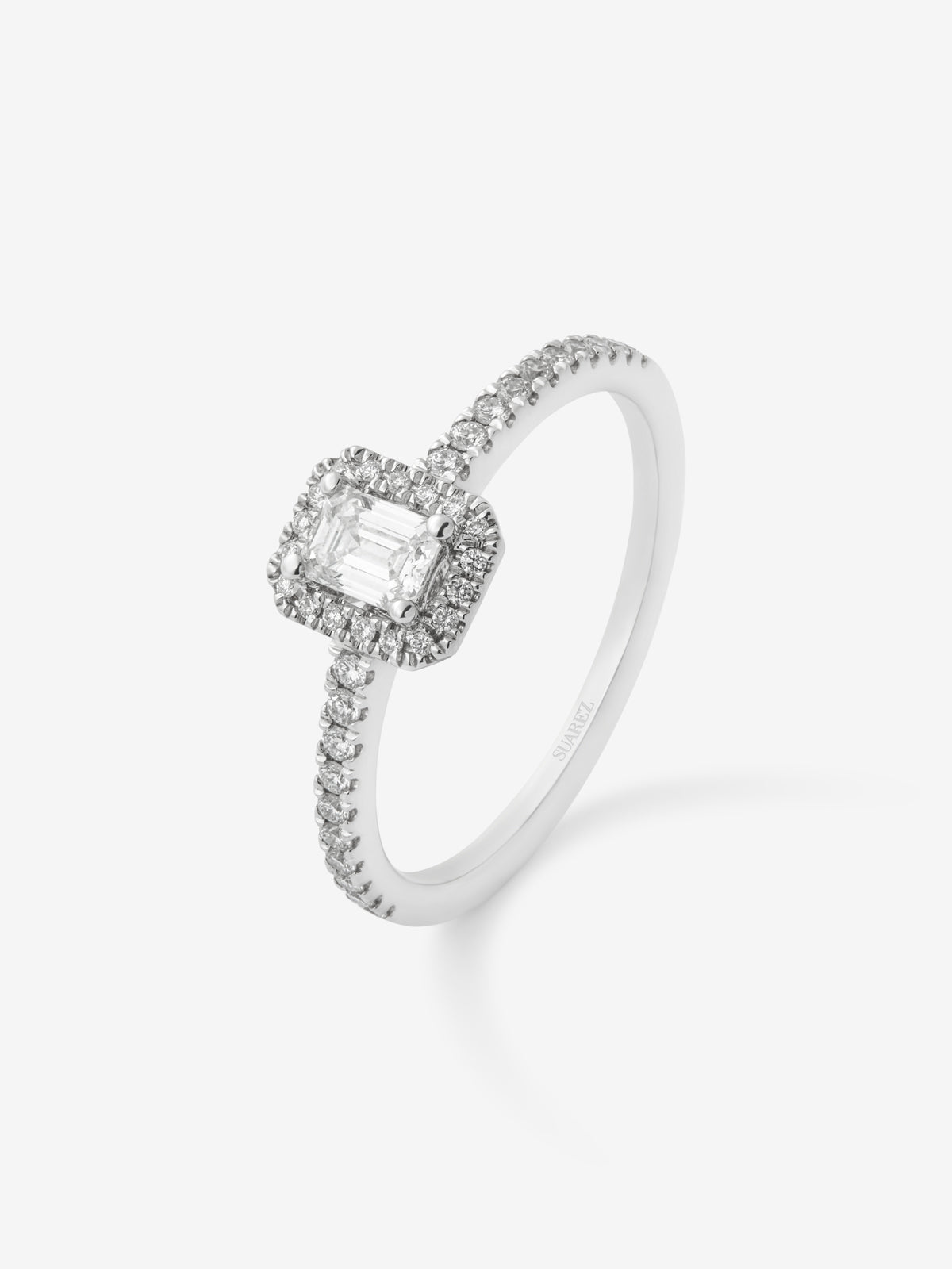 Anillo de oro blanco de 18K con diamante en talla esmeralda de 0,24 cts y orla de diamantes en talla brillante con un total de 0,17 cts
