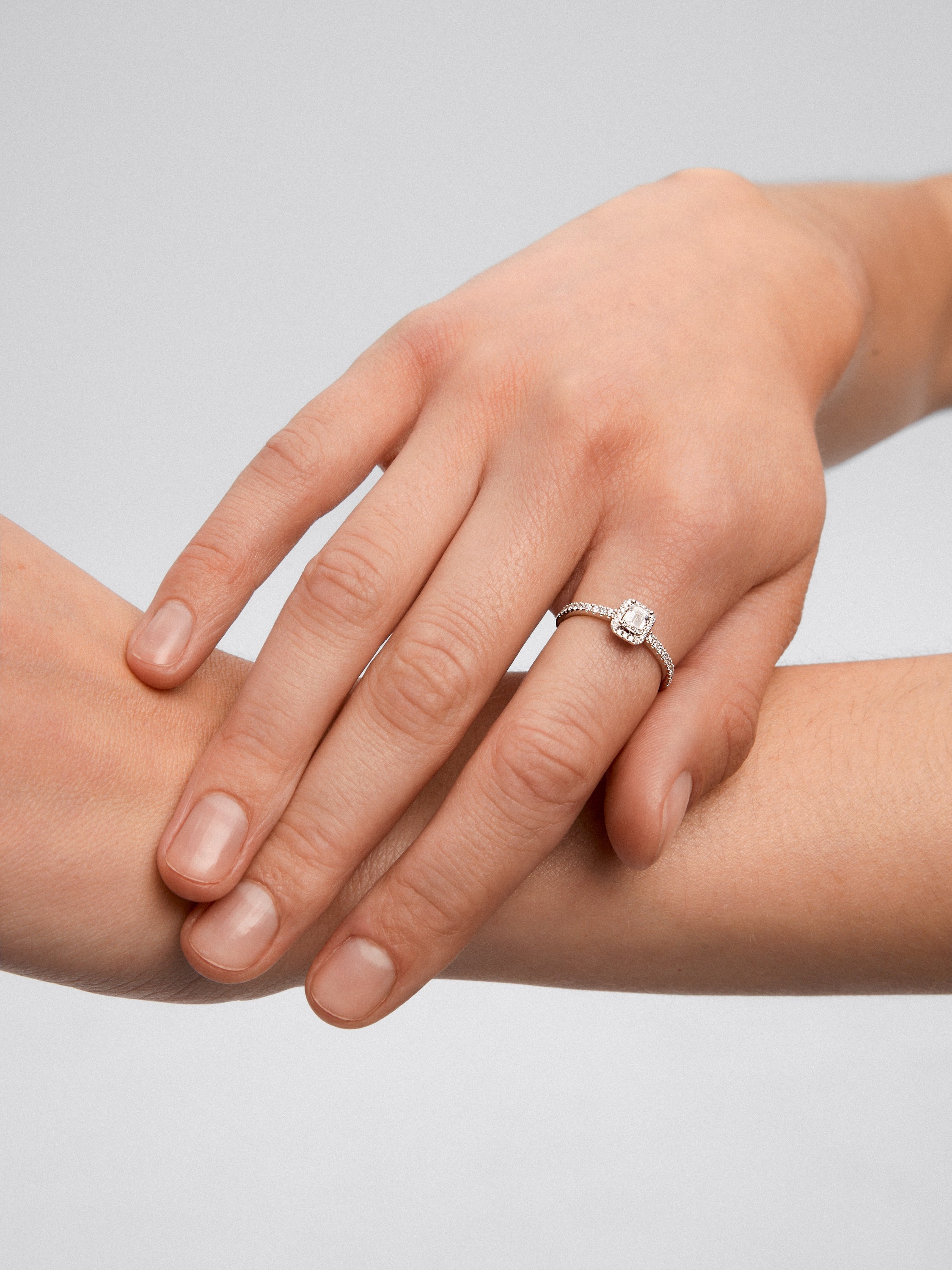 Anillo de oro blanco de 18K con diamante en talla esmeralda de 0,30 cts y orla de diamantes en talla brillante con un total de 0,19 cts