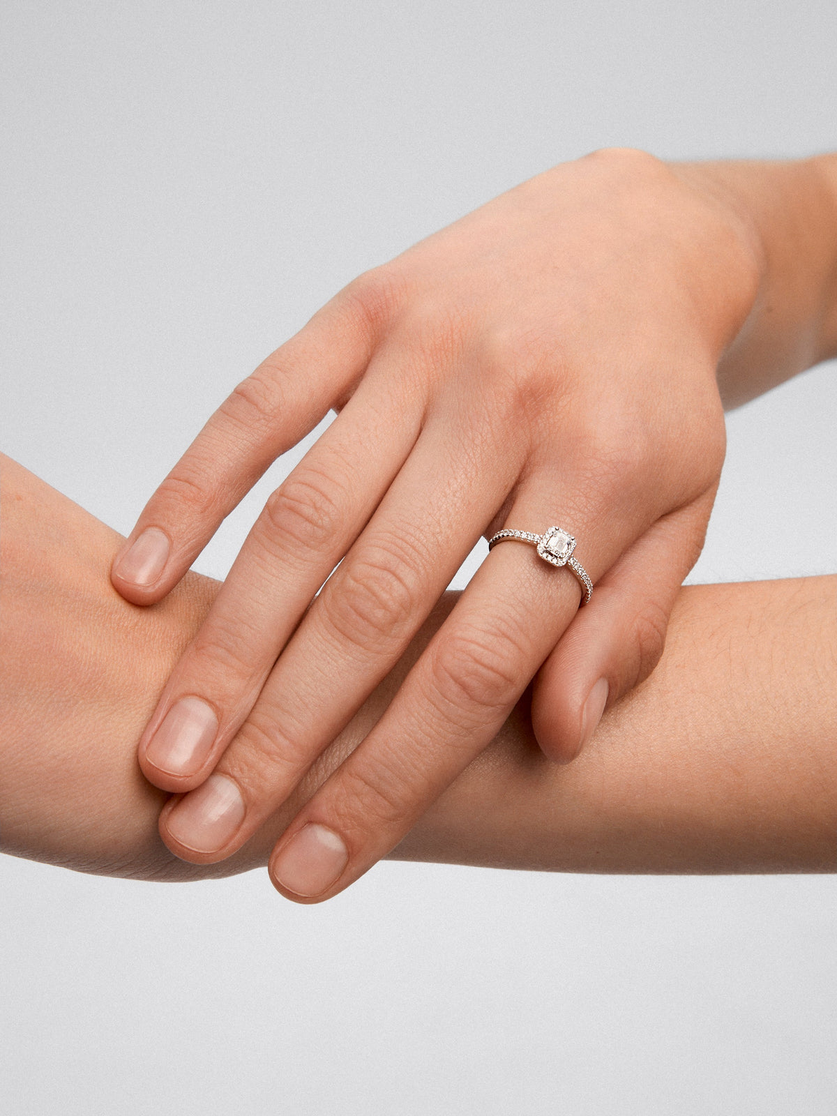 Anillo de oro blanco de 18K con diamante en talla esmeralda de 0,50 cts y orla de diamantes en talla brillante