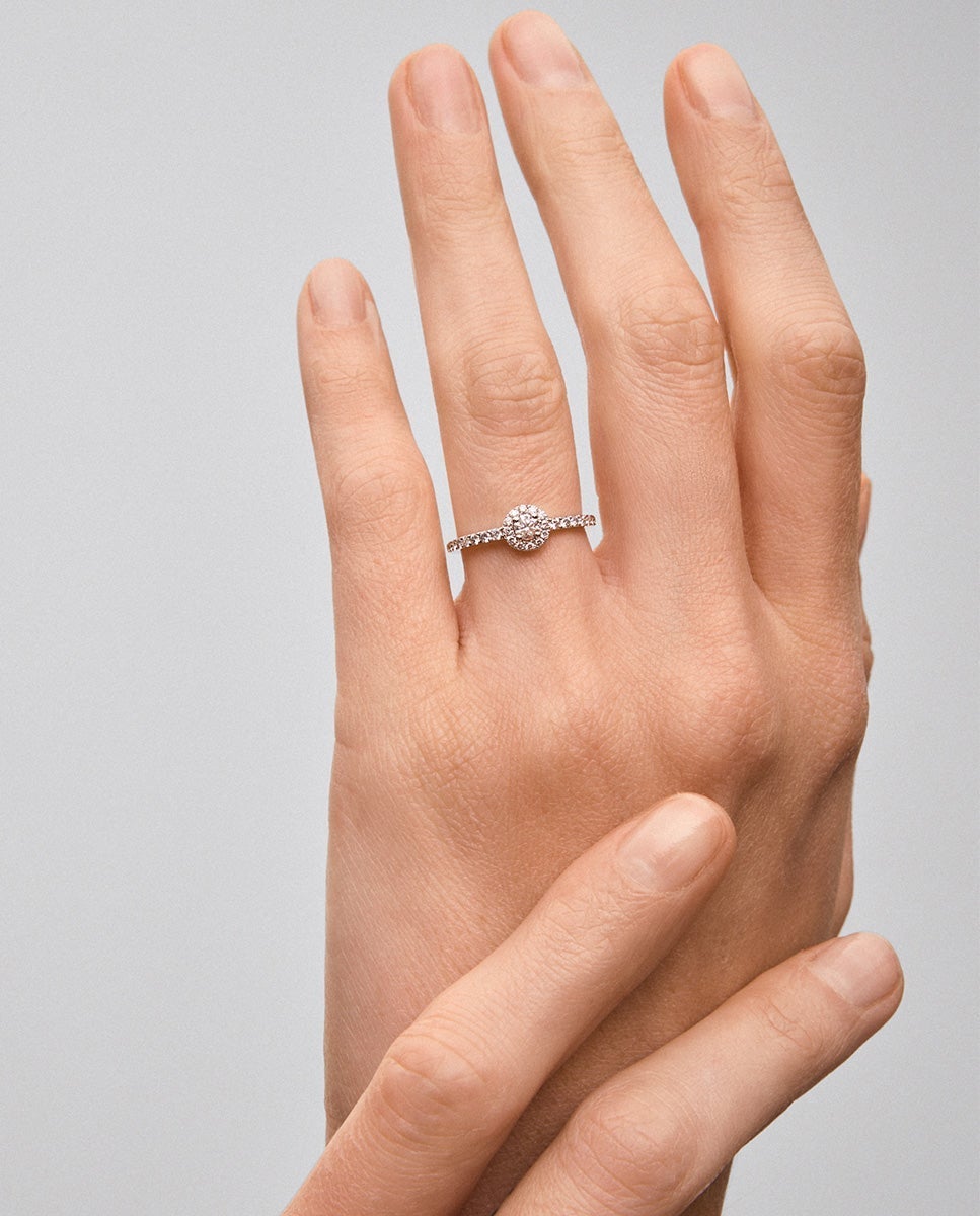 Anillo de oro blanco de 18K con diamante central en talla brillante de 0,15 cts y orla y brazo de 28 diamantes en talla brillante con un total de 0,3 cts