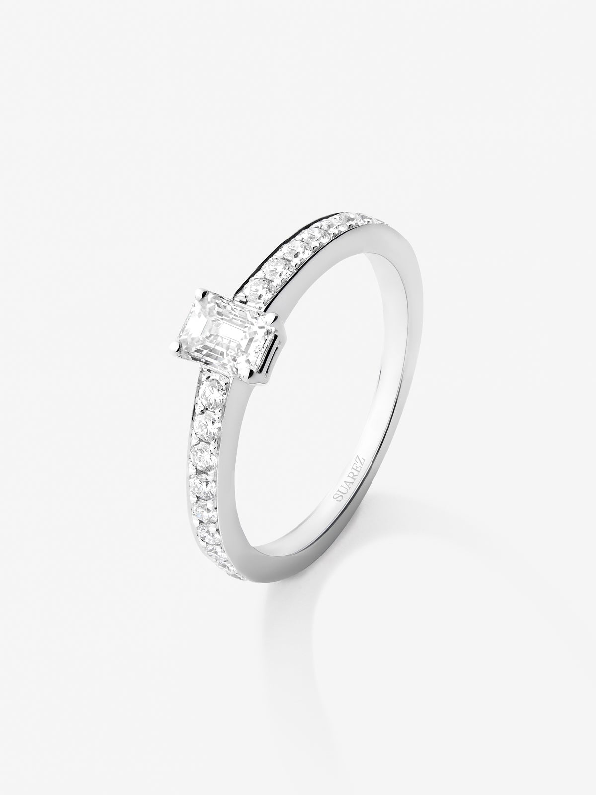 Anillo de oro blanco de 18K con diamante central en talla esmeralda de 0,40 y brazo de  diamantes en talla brillante