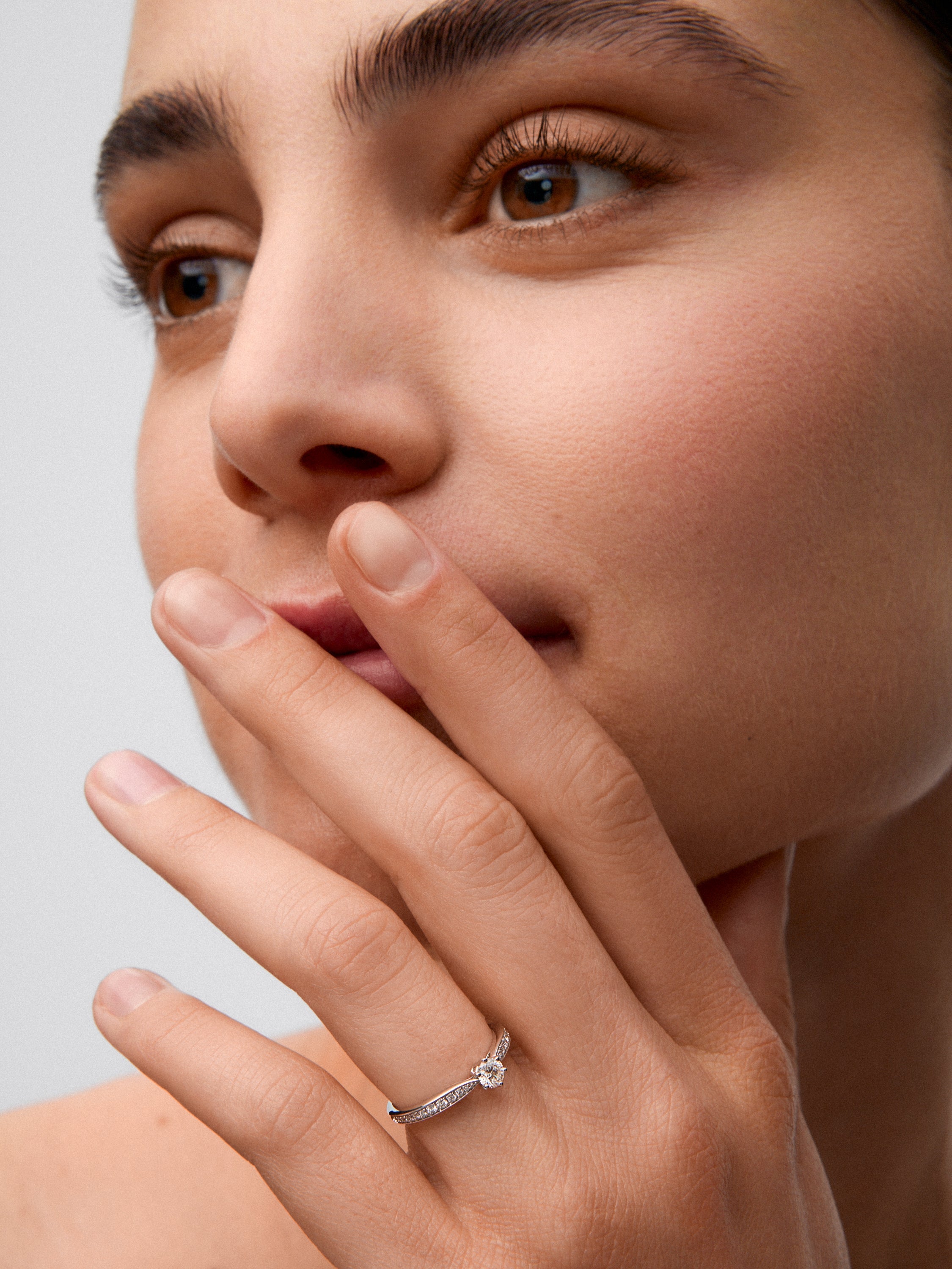 Anillo solitario de oro blanco de 18K con diamante central en talla brillante de 0,20 cts y diamantes en talla brillante con un total de 0,10 cts