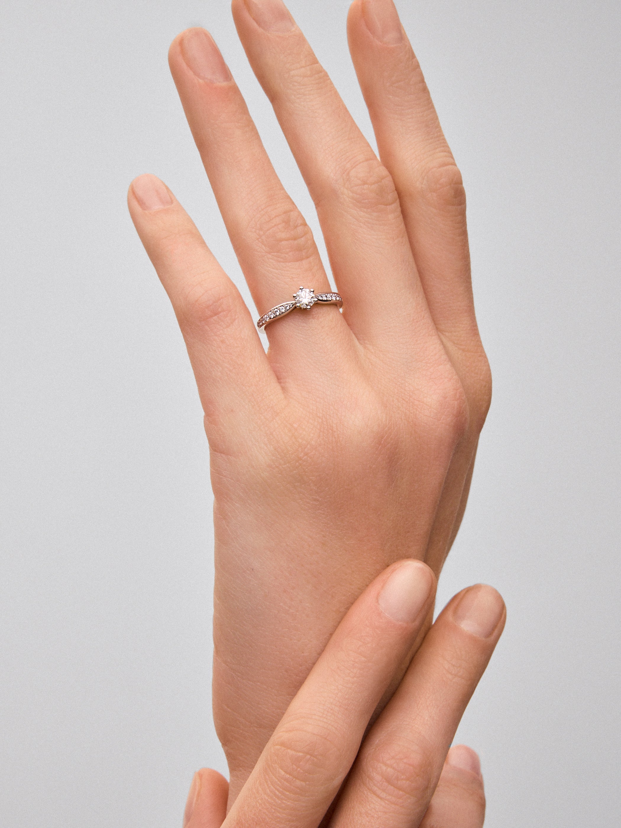 Anillo solitario de oro blanco de 18K con diamante central en talla brillante de 0,32 cts y diamantes en talla brillante con un total de 0,15 cts