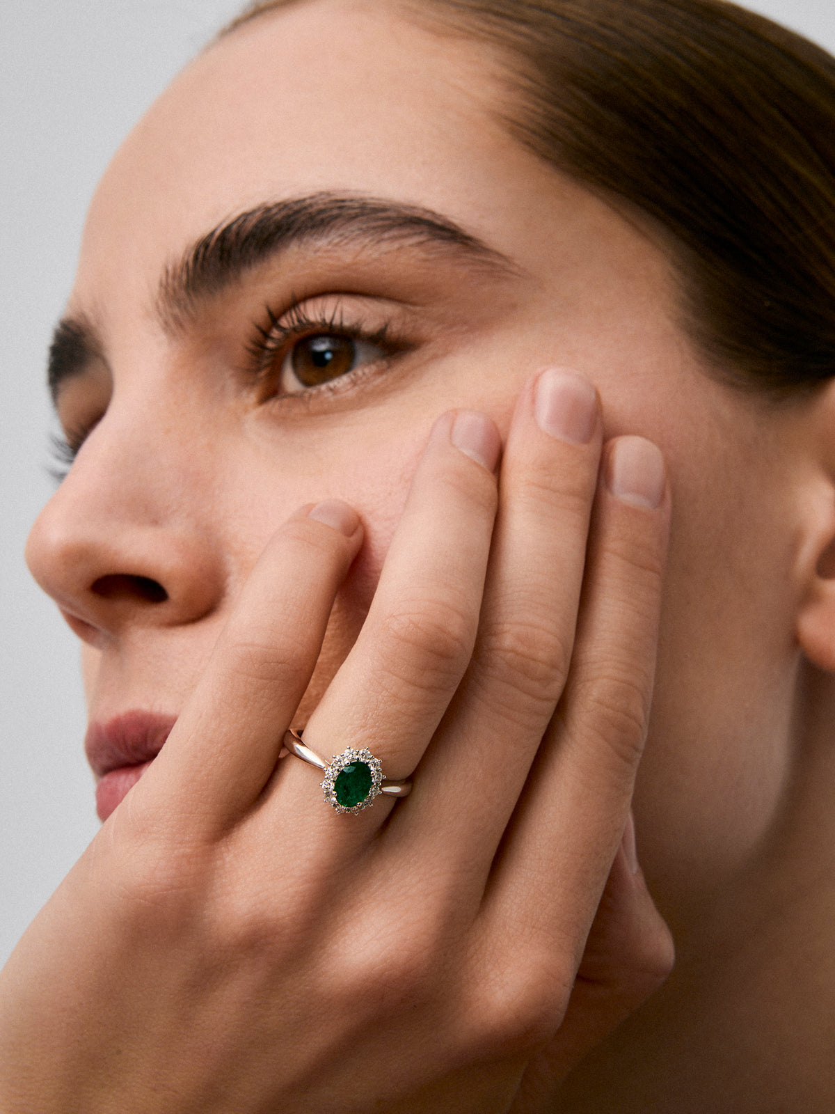 Anillo de oro blanco de 18K con esmeralda central en talla oval de 0,70 cts y orla de diamantes en talla brillante con un total de 0,30 cts