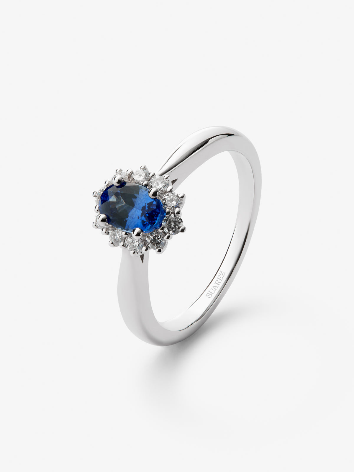 Anillo de oro blanco de 18K con zafiro azul central en talla oval de 0,60 cts y orla de diamantes en talla brillante