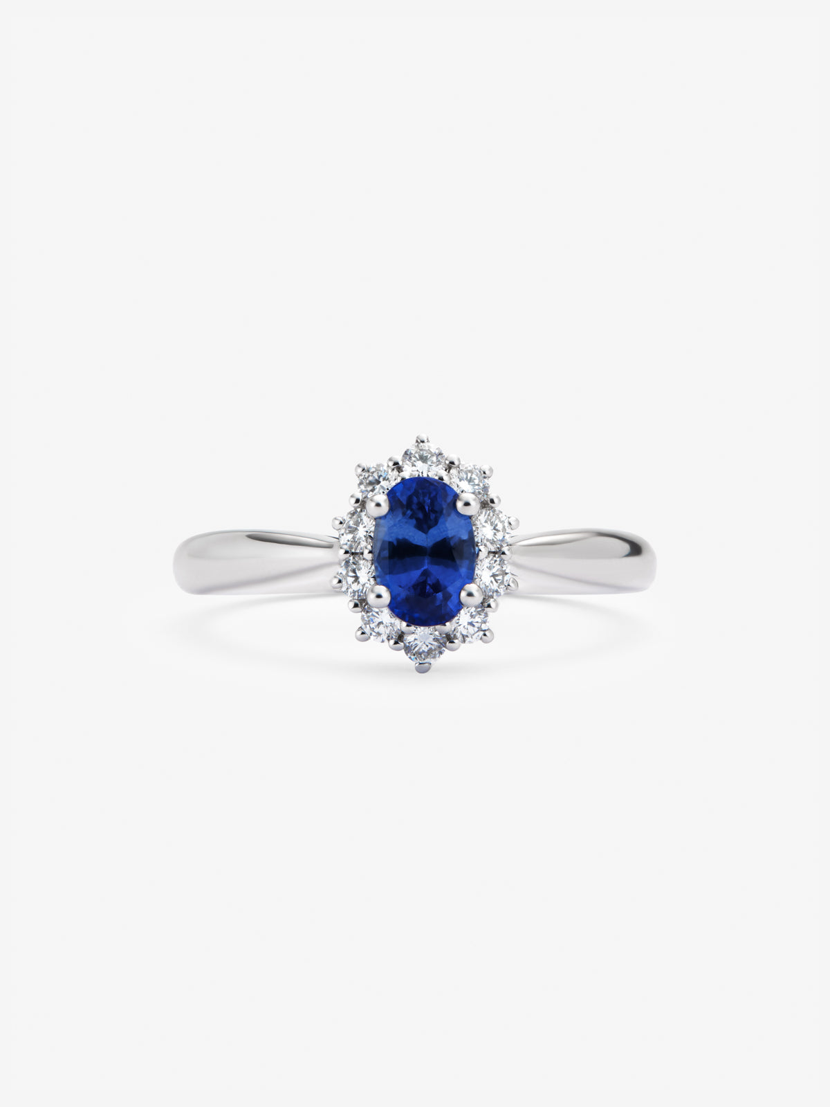 Anillo de oro blanco de 18K con zafiro azul central en talla oval de 0,60 cts y orla de diamantes en talla brillante