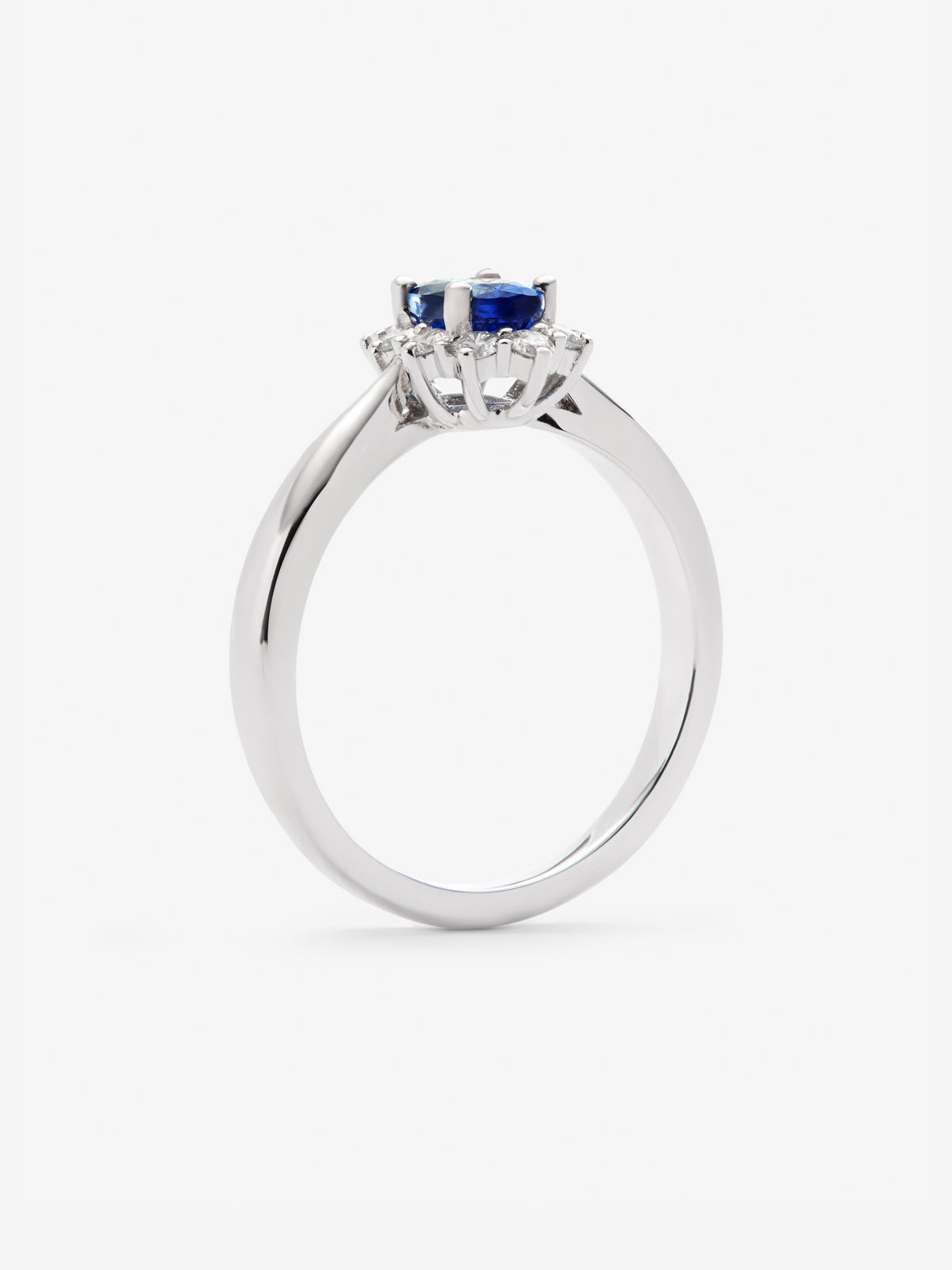 Anillo de oro blanco de 18K con zafiro azul central en talla oval de 0,60 cts y orla de diamantes en talla brillante