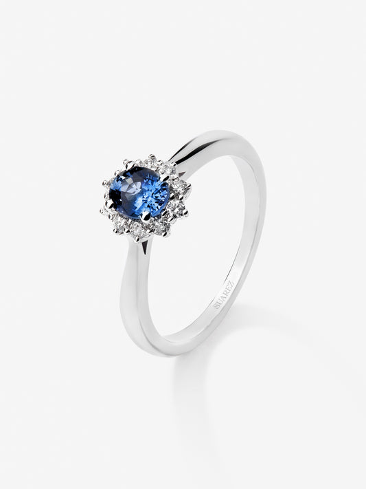 Anillo de oro blanco de 18K con zafiro azul central en talla oval de 0,30 cts y orla de diamantes en talla brillante