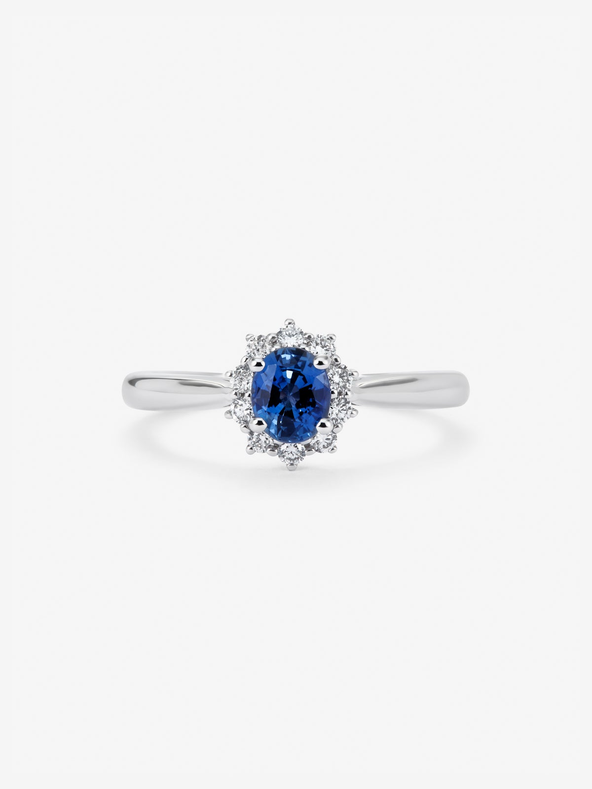 Anillo de oro blanco de 18K con zafiro azul central en talla oval de 0,30 cts y orla de diamantes en talla brillante con un total de 0,12 cts