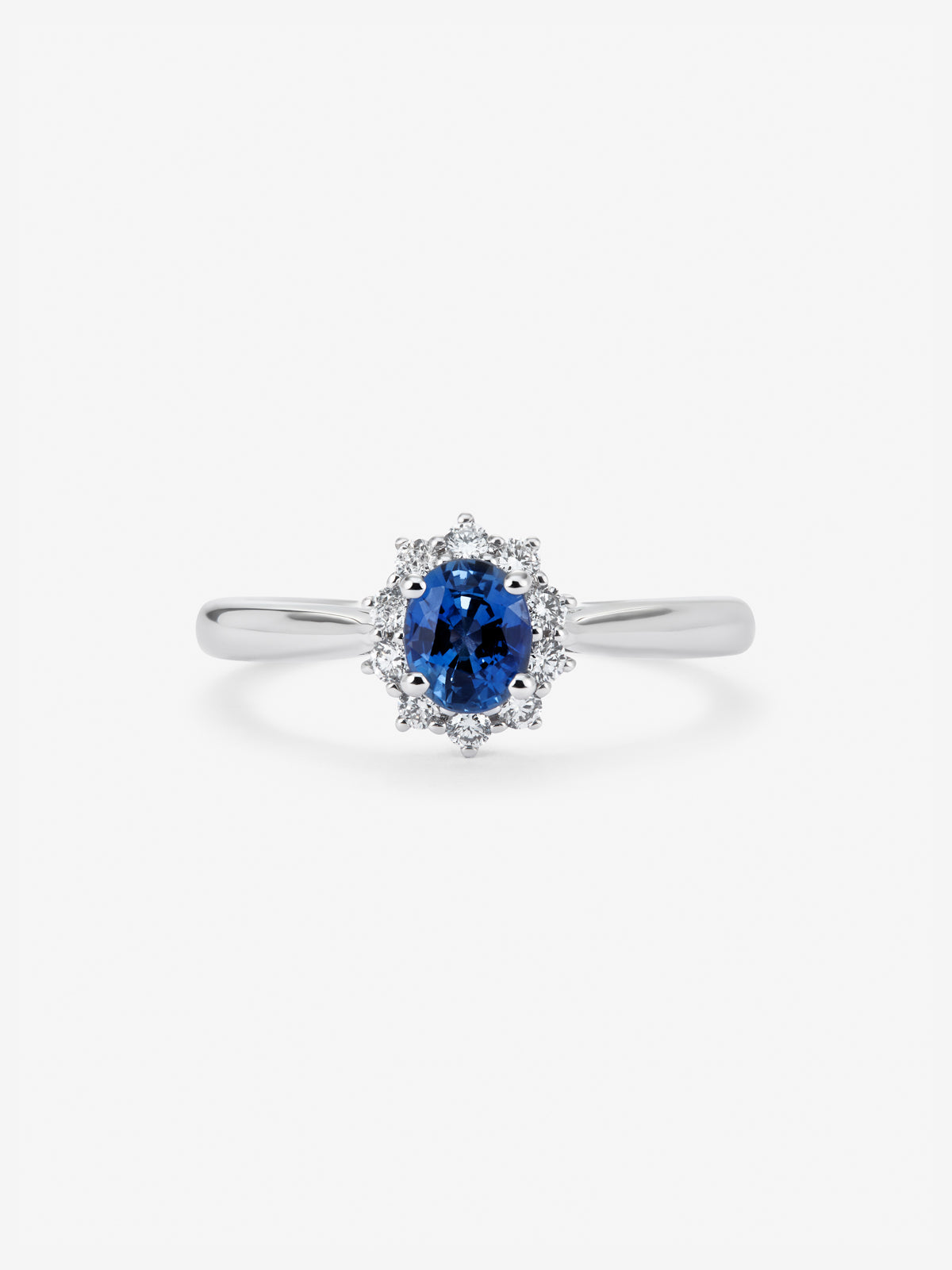 Anillo de oro blanco de 18K con zafiro azul central en talla oval de 0,30 cts y orla de diamantes en talla brillante