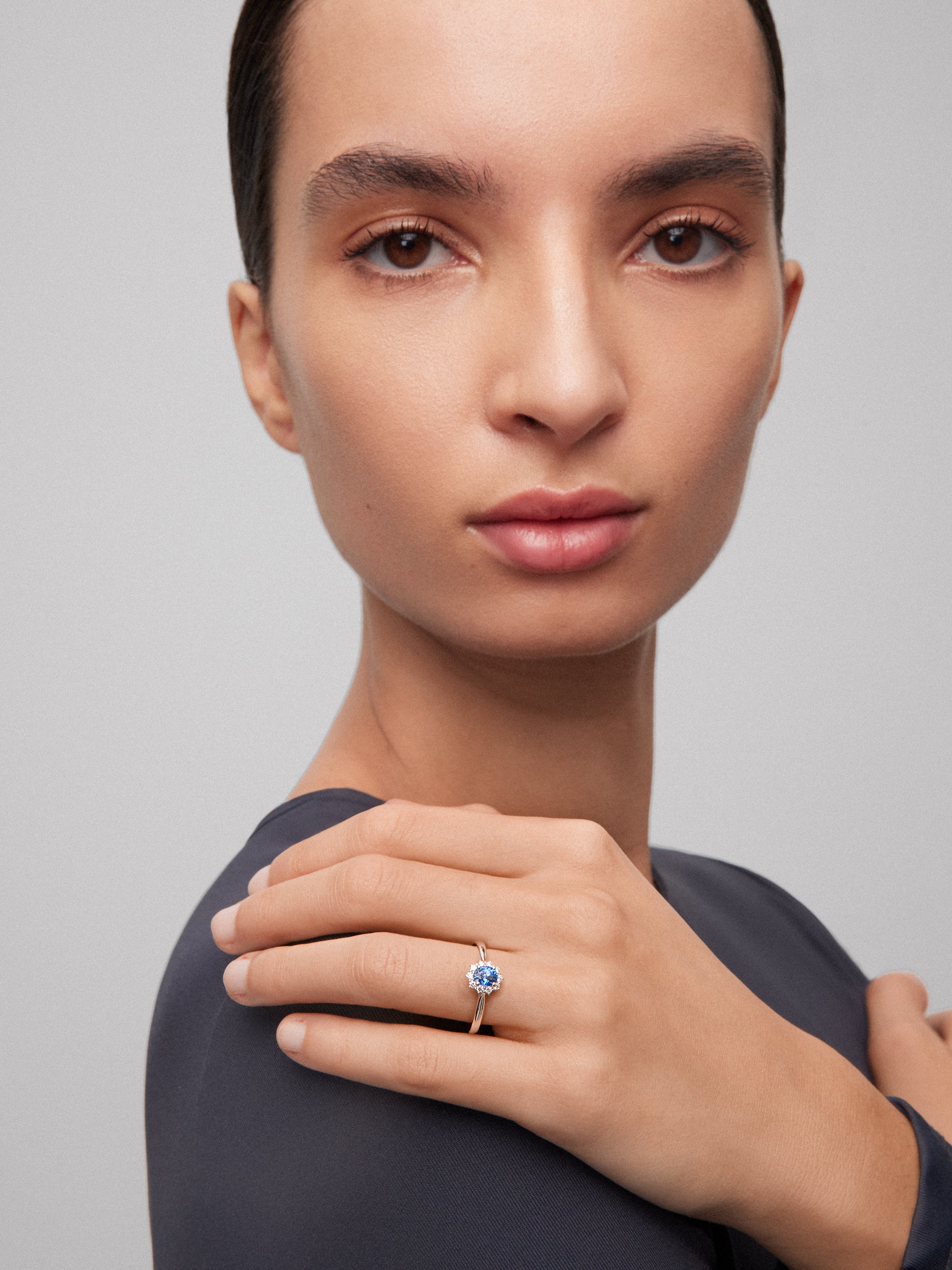 Anillo de oro blanco de 18K con zafiro azul central en talla oval de 0,4 cts y orla de diamantes en talla brillante con un total de 0,25 cts