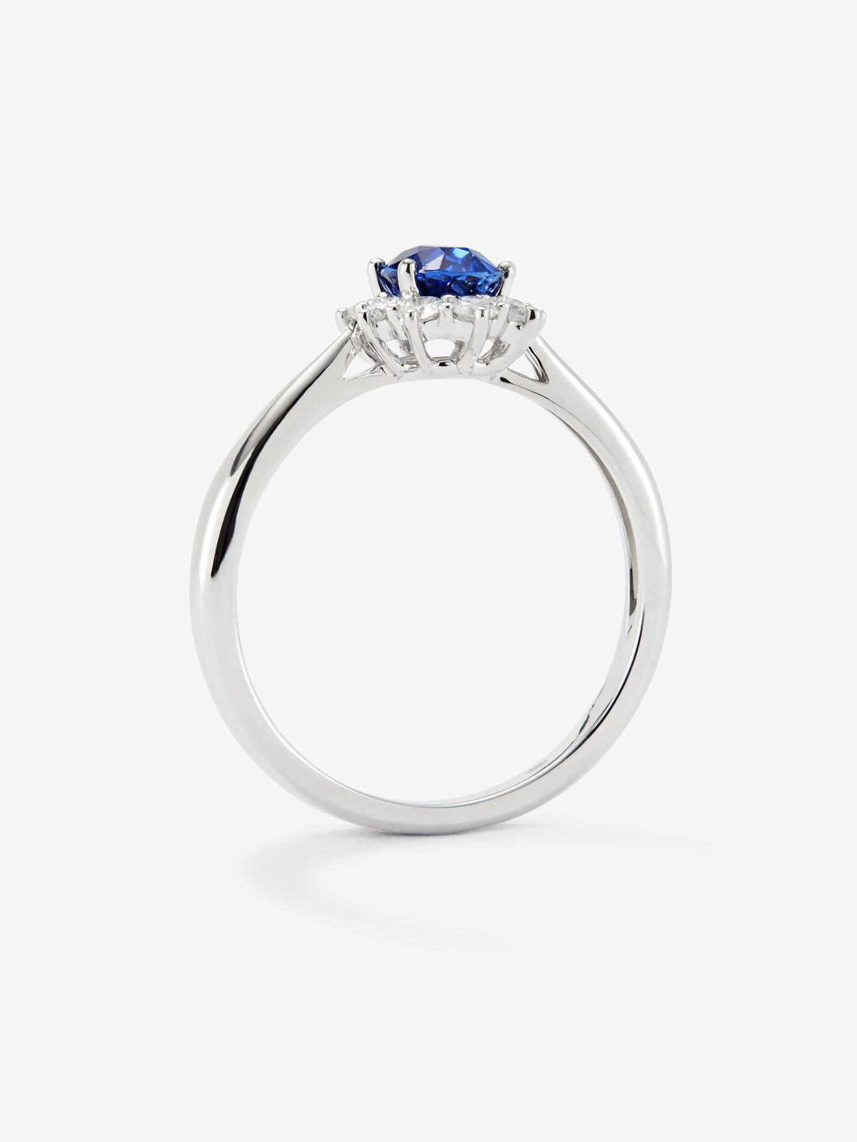 18K white gold ring with a central oval-cut blue sapphire of 0.4 cts and a border of brilliant-cut diamonds totaling 0.25 cts.