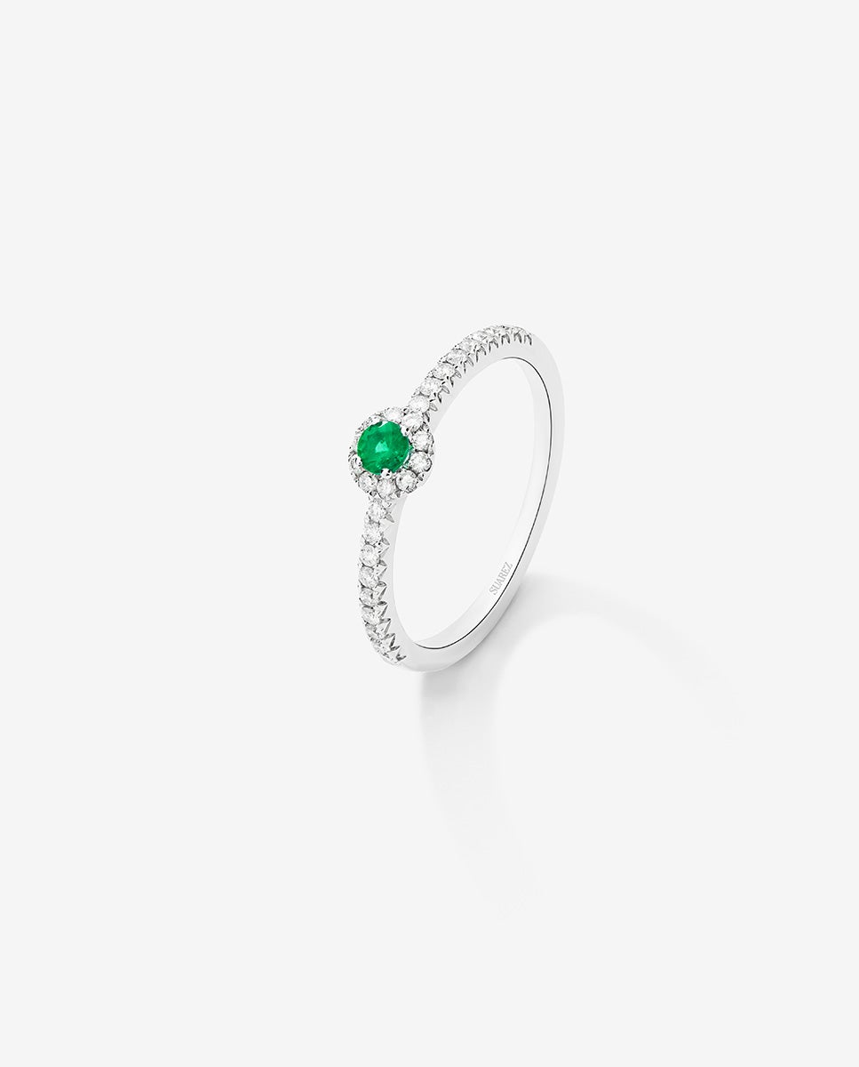 Anillo de oro blanco de 18K con esmeralda en talla brillante de 0,15 cts y brazo y orla de 26 diamantes en talla brillante con un total de 0,27 cts