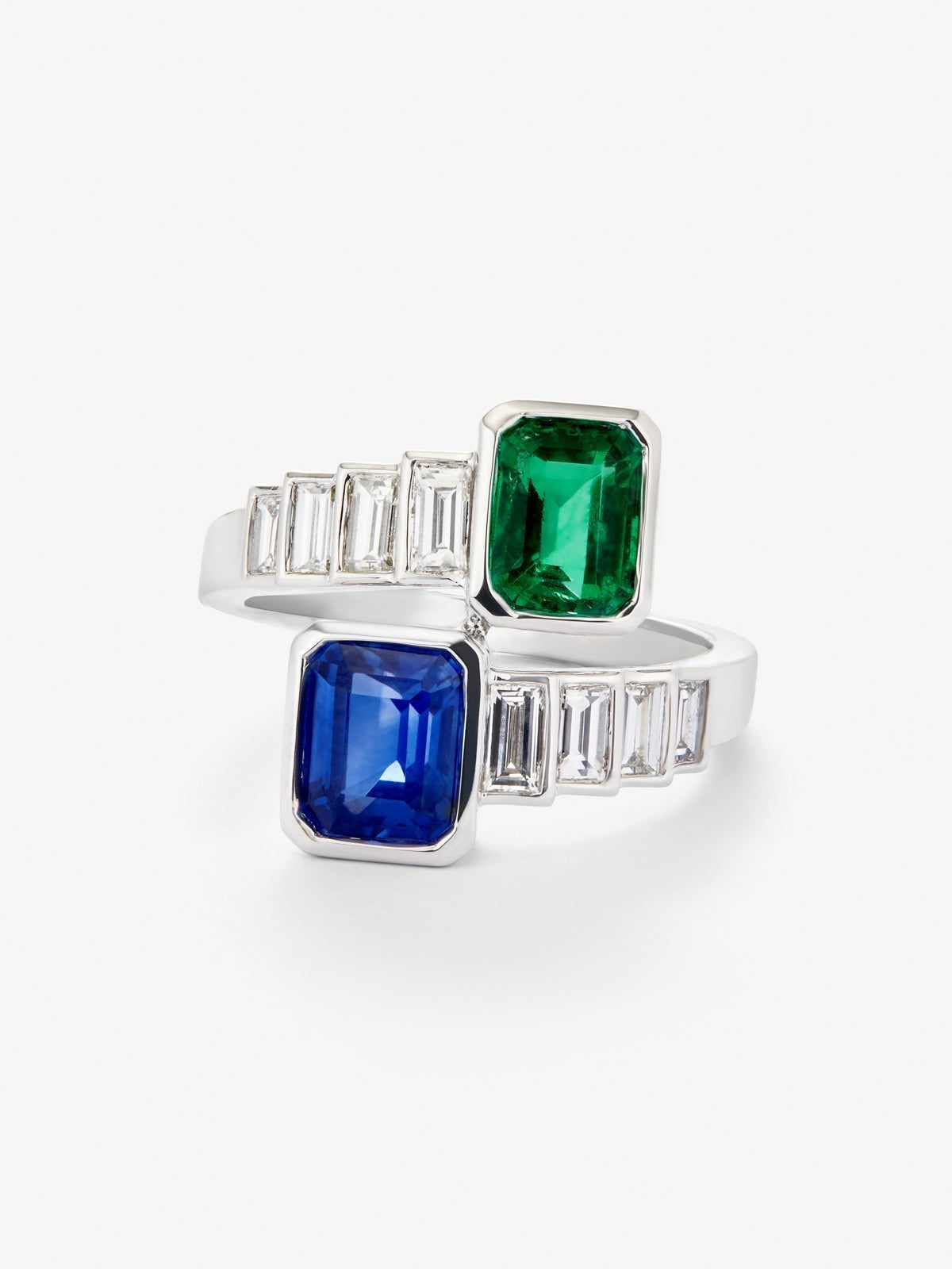 Anillo tú y yo de oro blanco de 18K con un zafiro azul en talla octogonal de 1,64 cts, una esmeralda verde en talla octogonal de 1,02 cts y 8 diamantes en talla baguette con un total de 0,72 cts