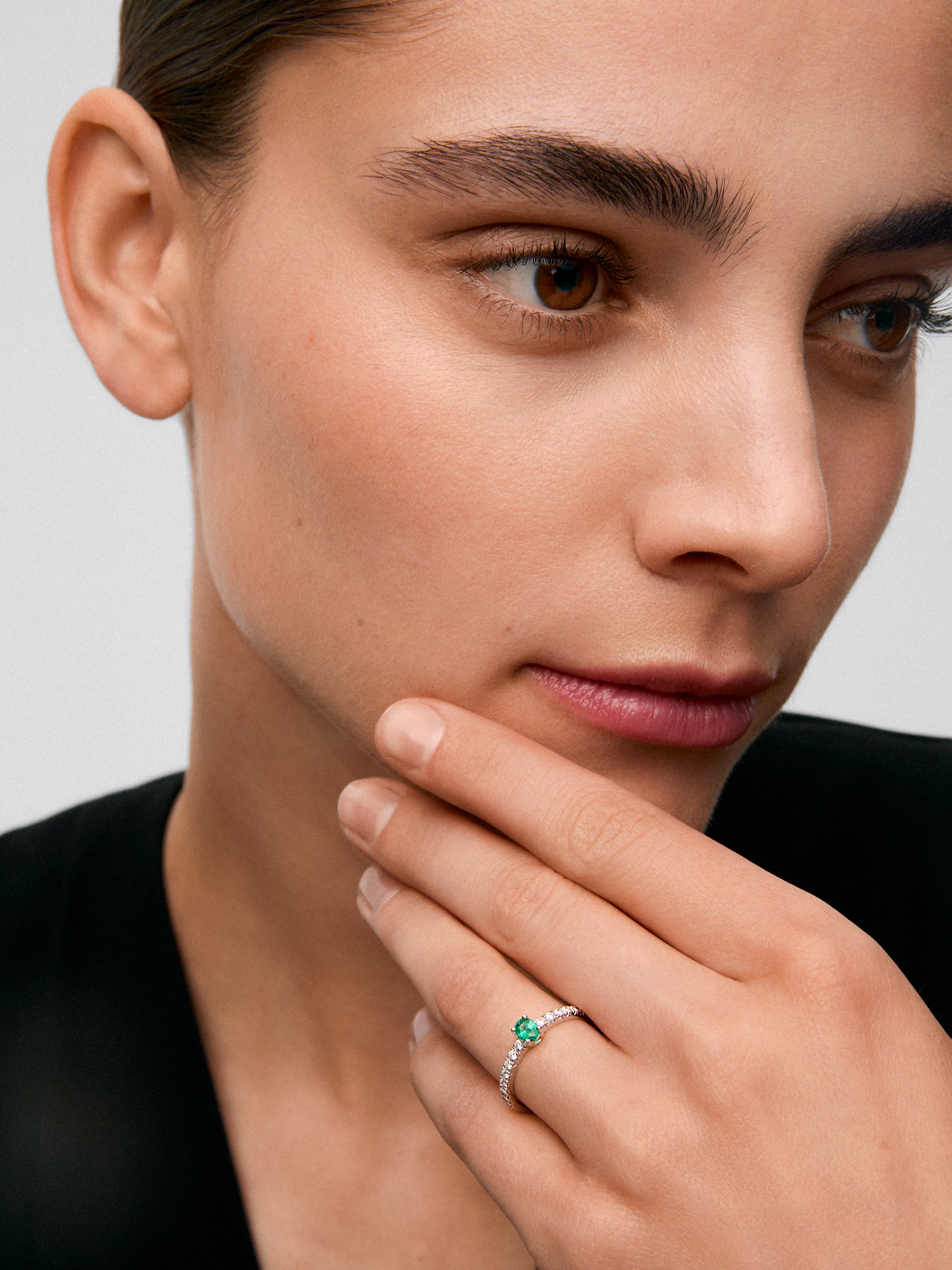 Anillo de oro blanco de 18K con una esmeralda verde en talla oval de 0,20 cts y 16 diamantes en talla brillante con un total de 0,21 cts