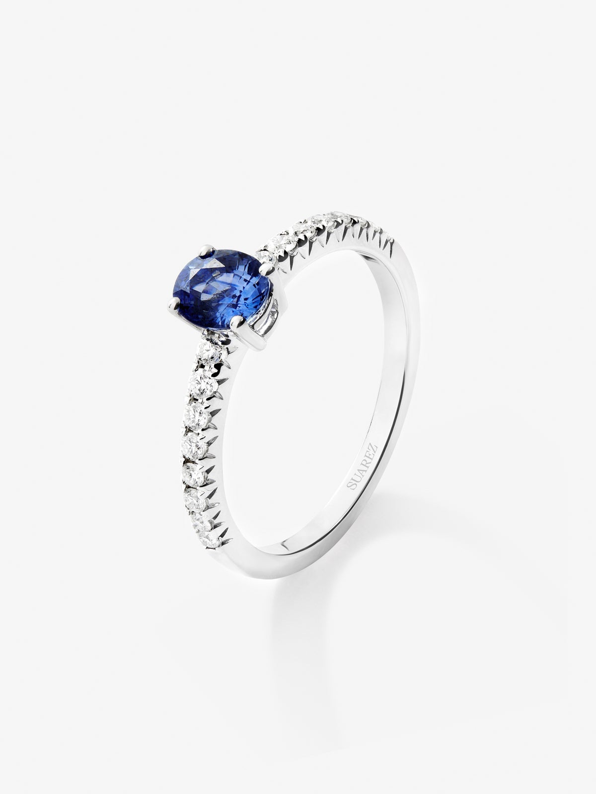 Anillo de oro blanco de 18K con zafiro azul en talla oval de 0,3 cts y brazo de 16 diamantes en talla brillante con un total de 0,2 cts