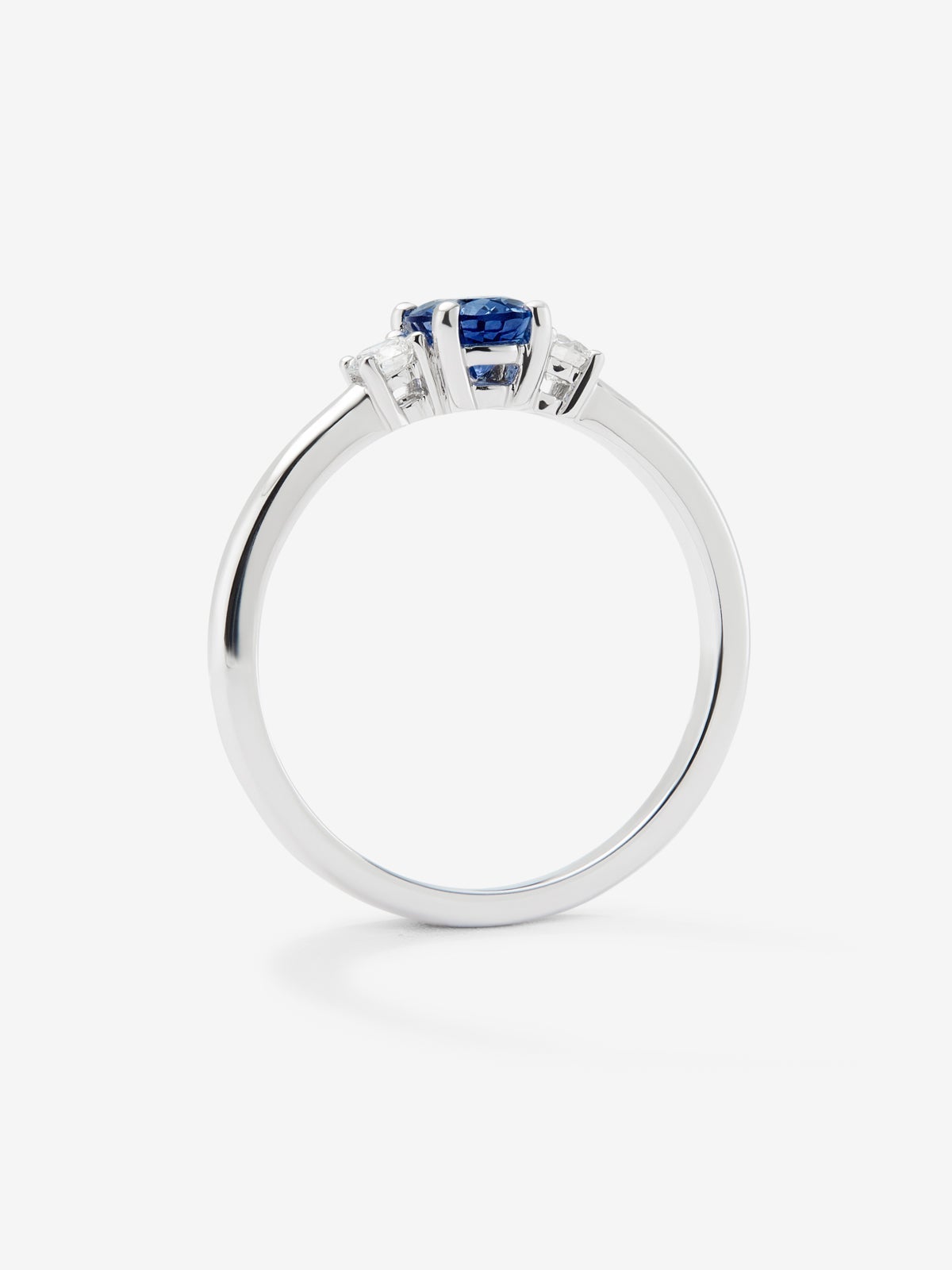 Anillo tresillo de oro blanco de 18K con zafiro azul en talla oval de 0,69 cts y 2 diamantes en talla brillante con un total de 0,16 cts