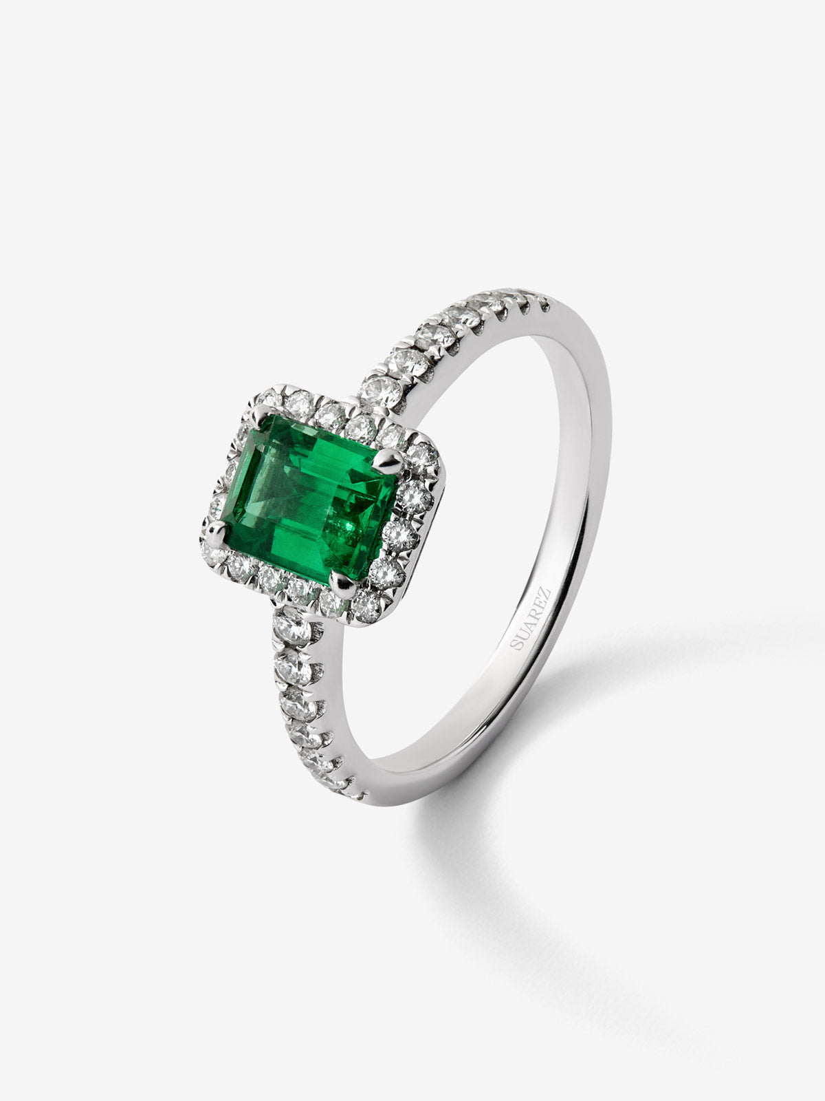 Anillo de oro blanco de 18K con esmeralda en talla esmeralda de 0,70cts y orla y brazo de 32 diamantes en talla brillante 
