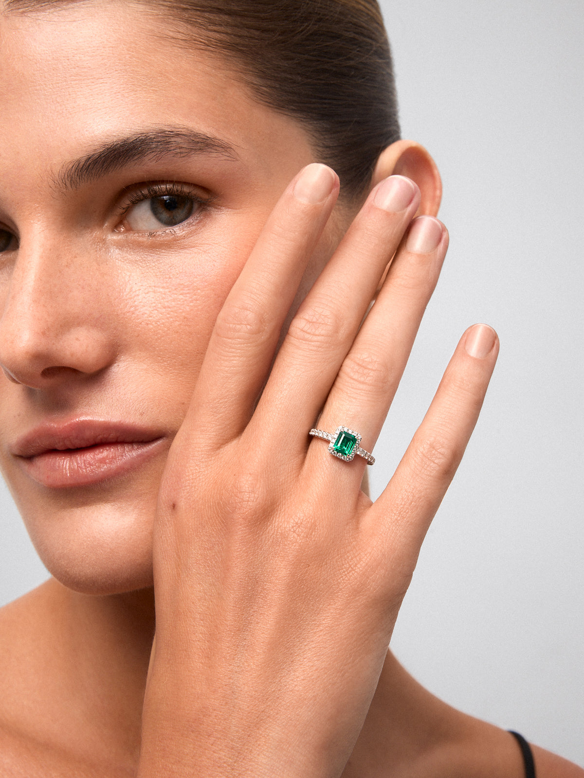 Anillo de oro blanco de 18K con esmeralda en talla esmeralda de 0,70cts y orla y brazo de 32 diamantes en talla brillante 