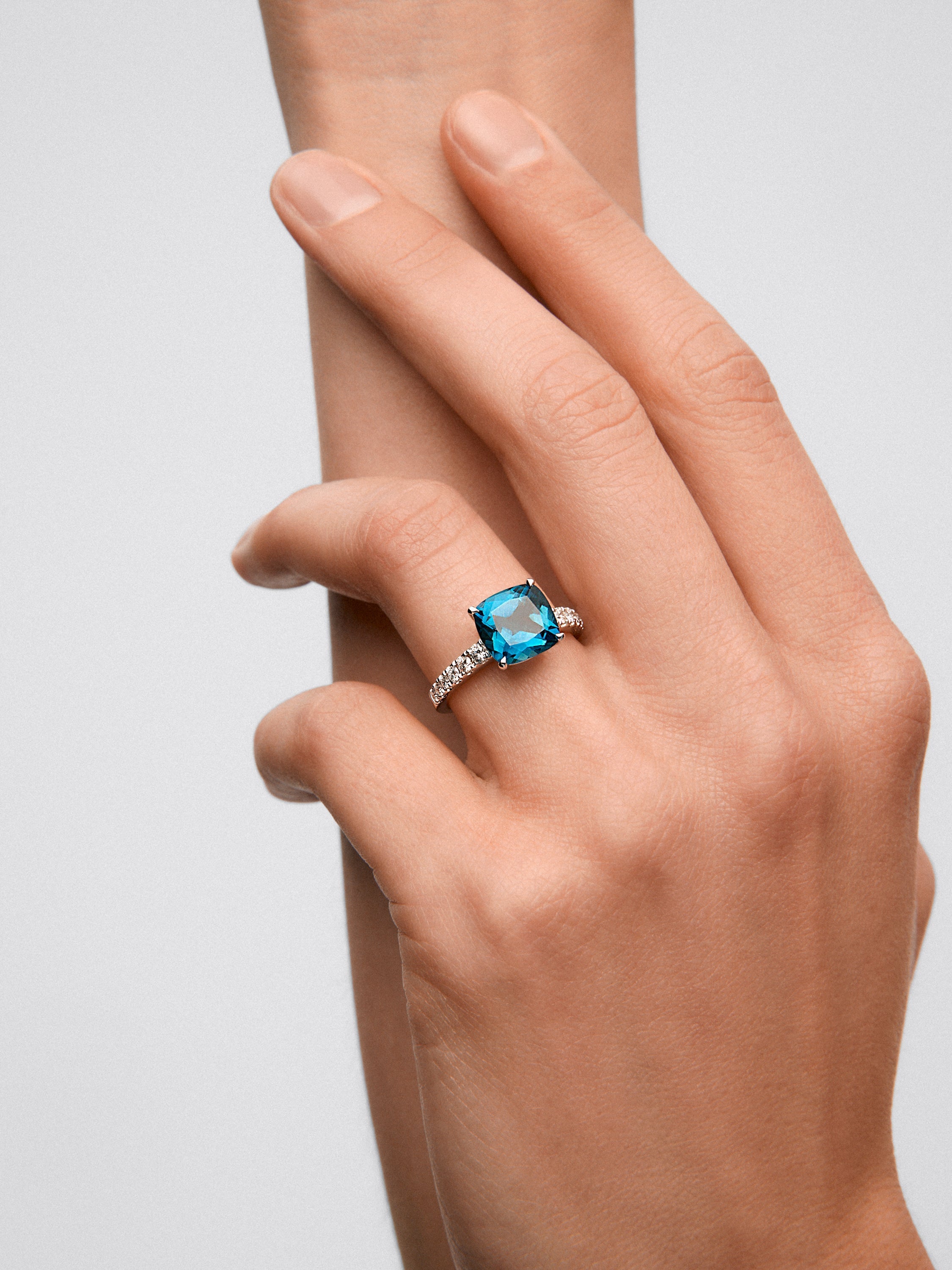 Anillo de oro blanco de 18K con topacio azul london en talla cushion de 3,8 cts y 12 diamantes en talla brillante con un total de 0,29 cts