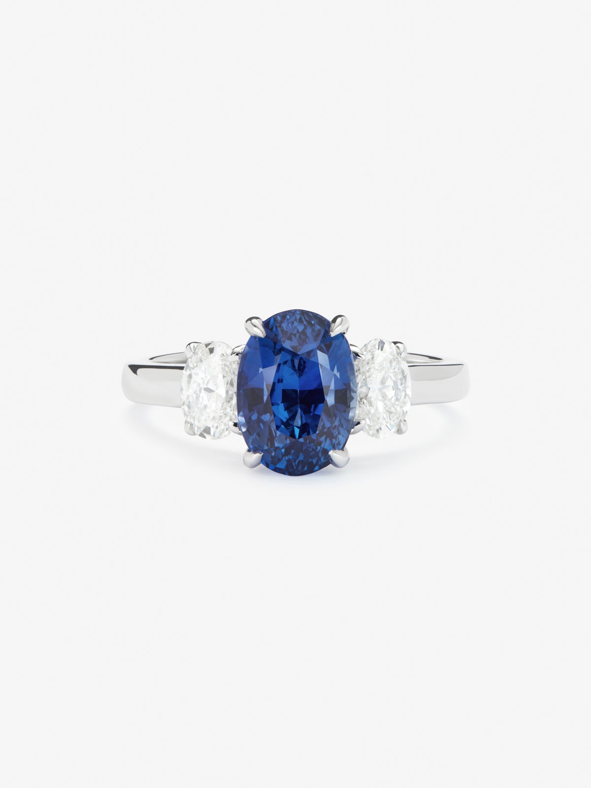 Anillo tresillo de oro blanco de 18K con zafiro azul royal en talla oval de 3,37 cts y 2 diamantes en talla oval con un total de 0,8 cts