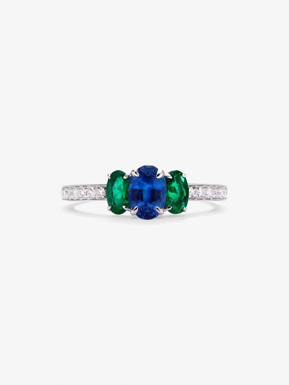 Anillo tresillo de oro blanco de 18K con zafiro azul en talla oval de 0,71 cts, 2 esmeraldas verdes en talla oval con un total de 0,5 cts y 10 diamantes en talla brillante con un total de 0,115 cts