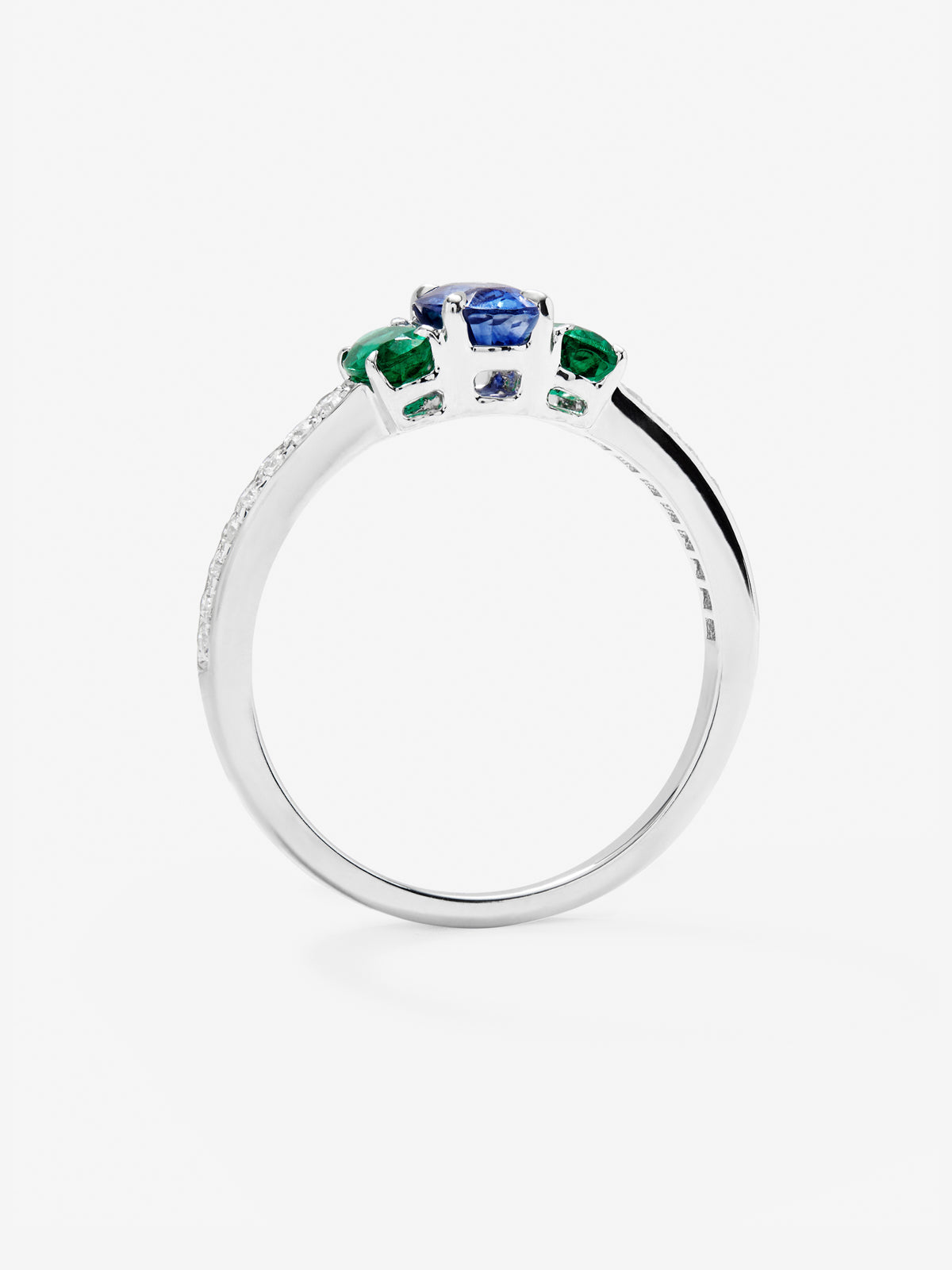 Anillo tresillo de oro blanco de 18K con zafiro azul en talla oval de 0,71 cts, 2 esmeraldas verdes en talla oval con un total de 0,5 cts y 10 diamantes en talla brillante con un total de 0,115 cts
